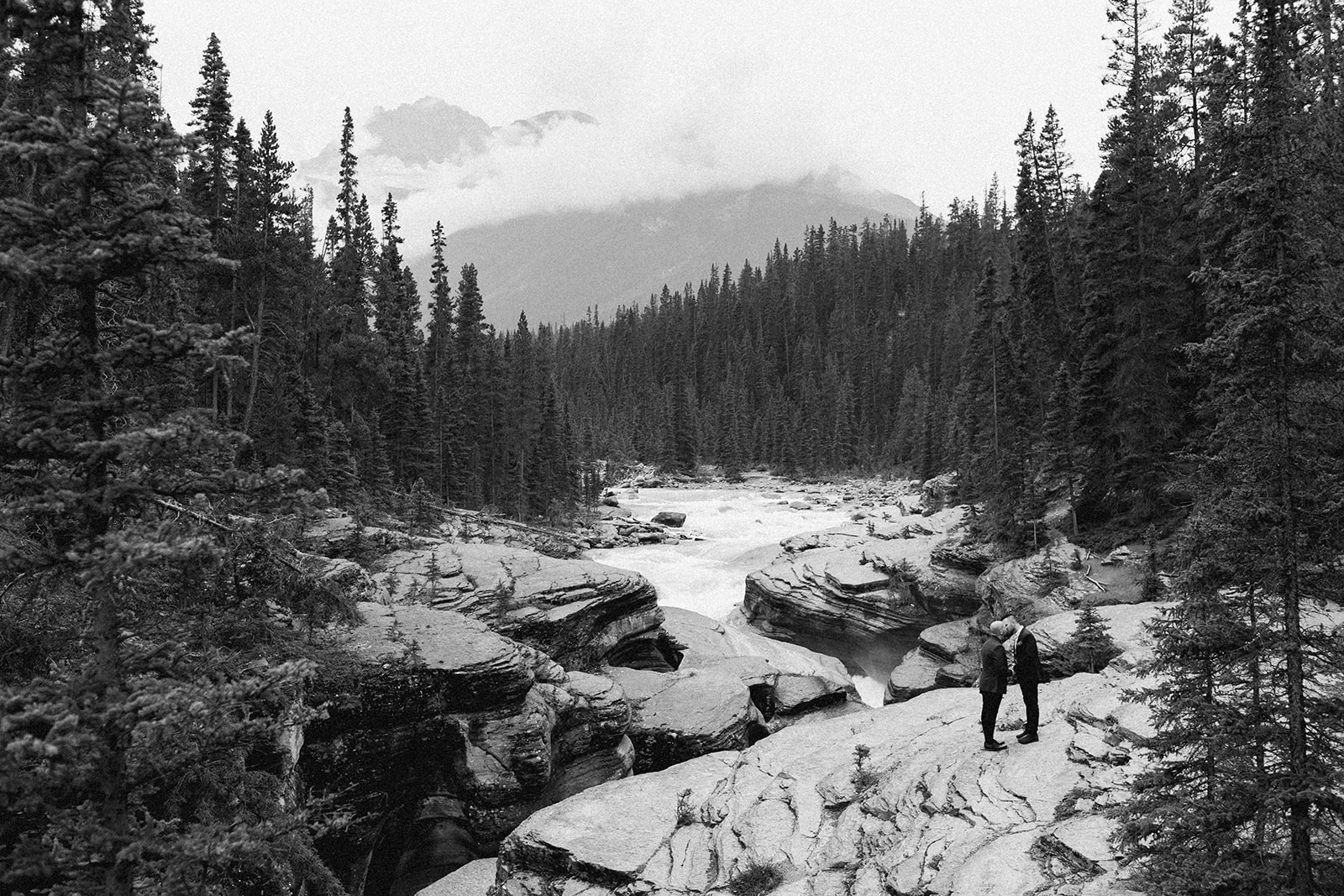 A Mistaya Canyon elopement couple kisses on a rock formation near Banff National Park. 