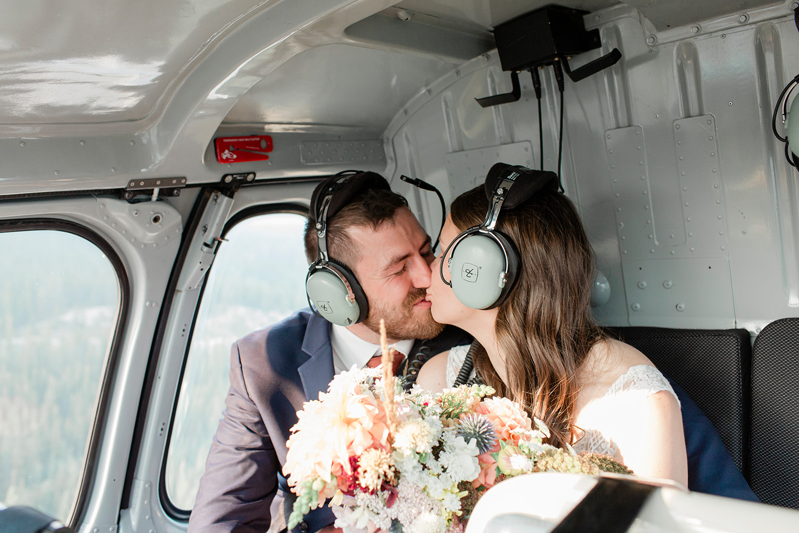 A couple kisses while riding in a Rockies Heli helicopter during a Banff helicopter wedding.