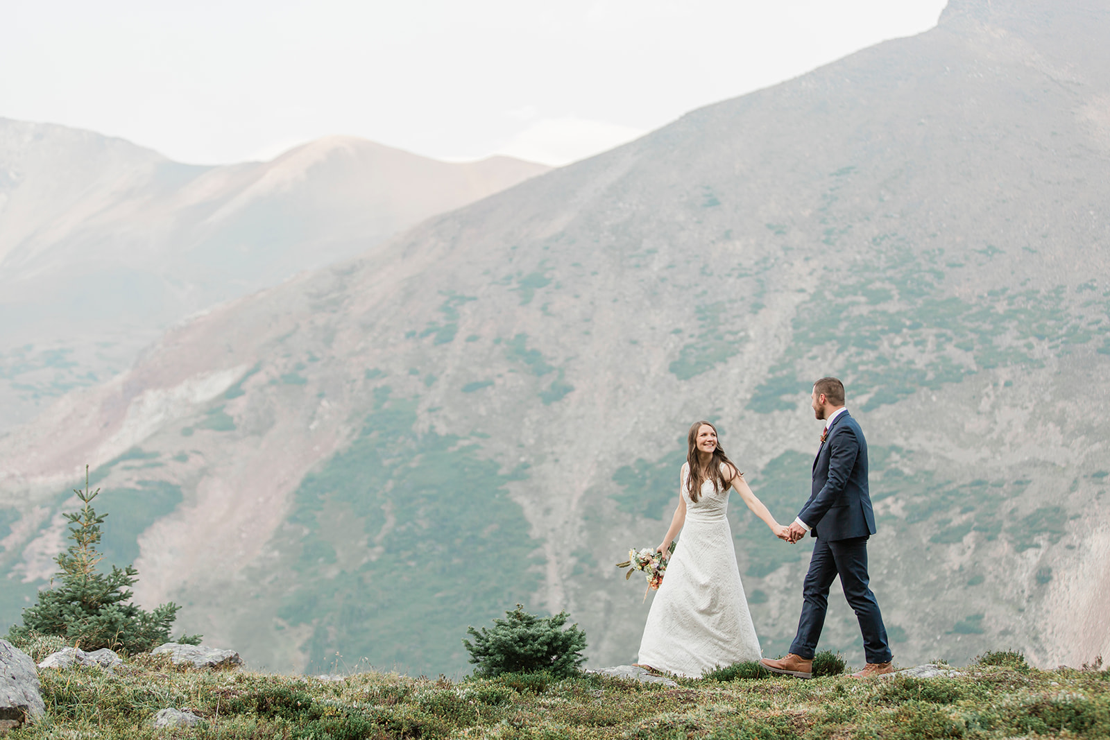 A Banff helicopter wedding couple walks along a ridge that overlooks Banff and it's mountains. 