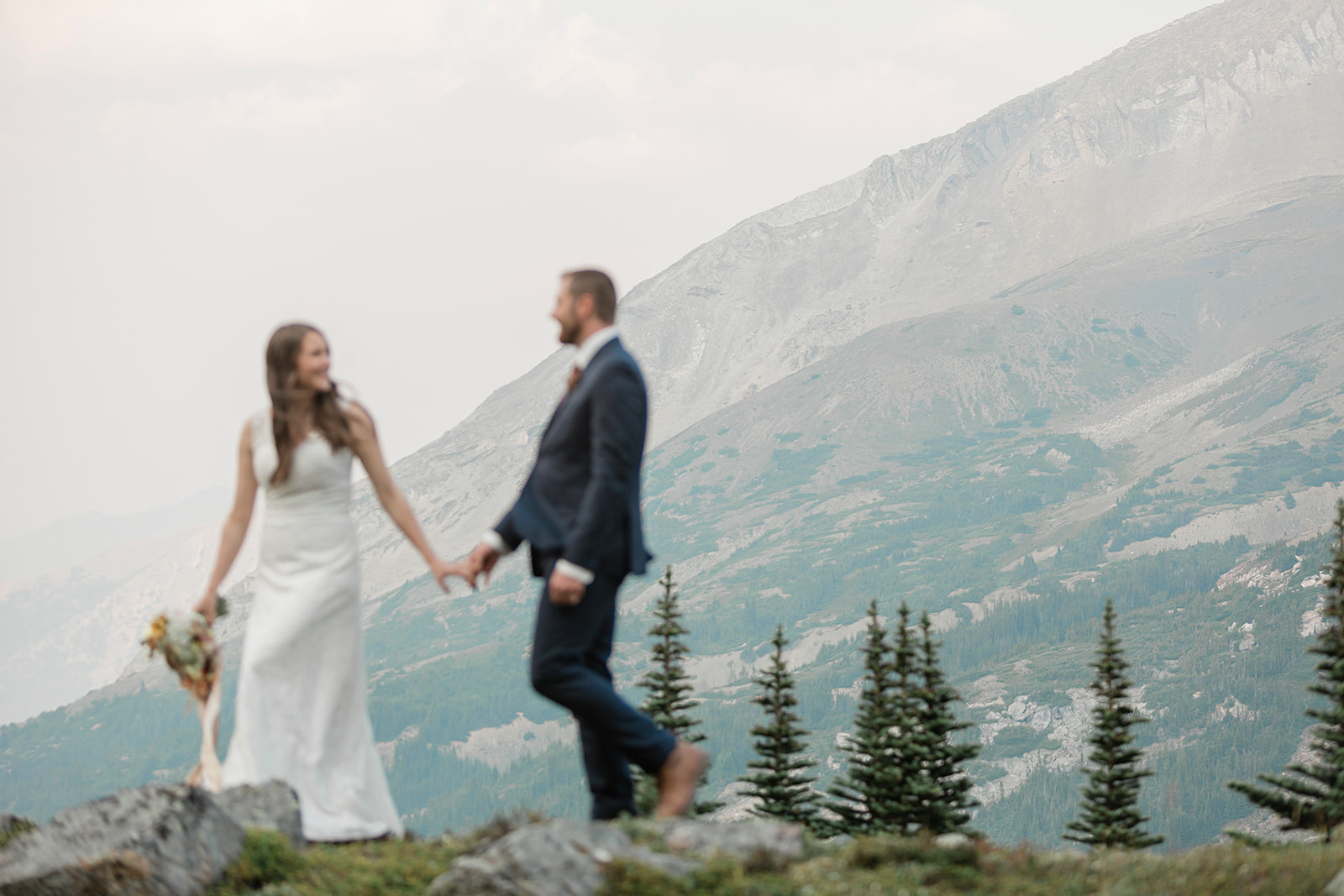 A Banff helicopter wedding couple walks along a ridge that overlooks Banff and it's mountains. 