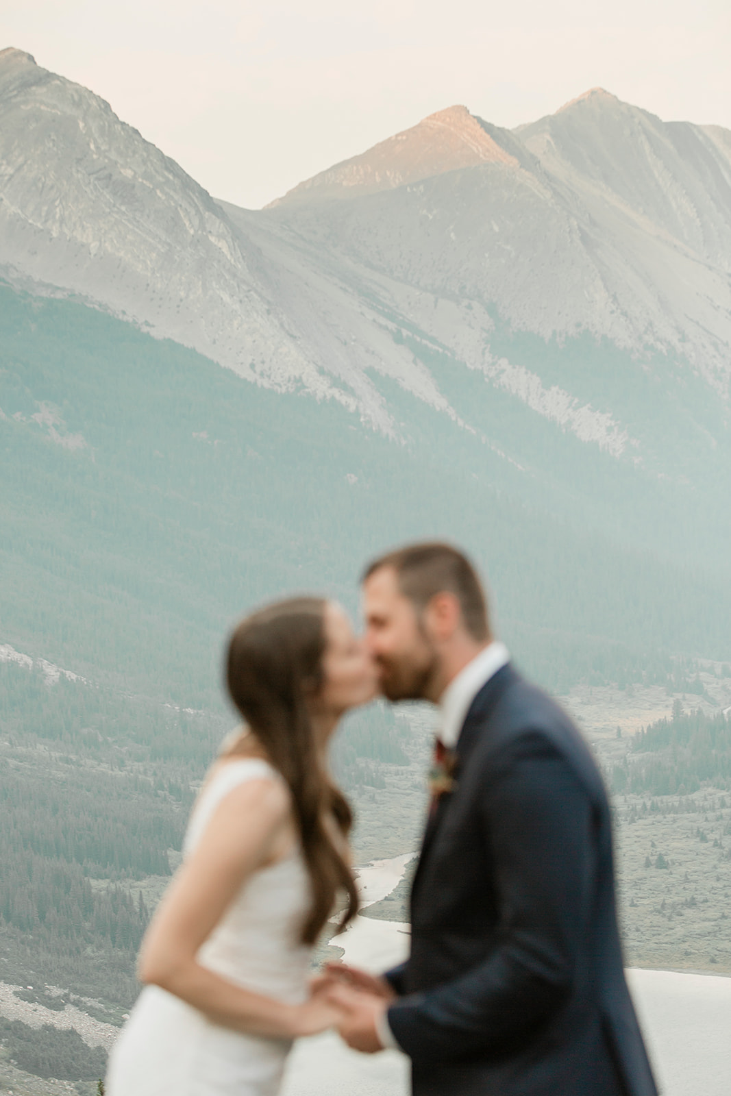 A Banff helicopter wedding couple kisses during their ceremony overlooking an alpine lake. 