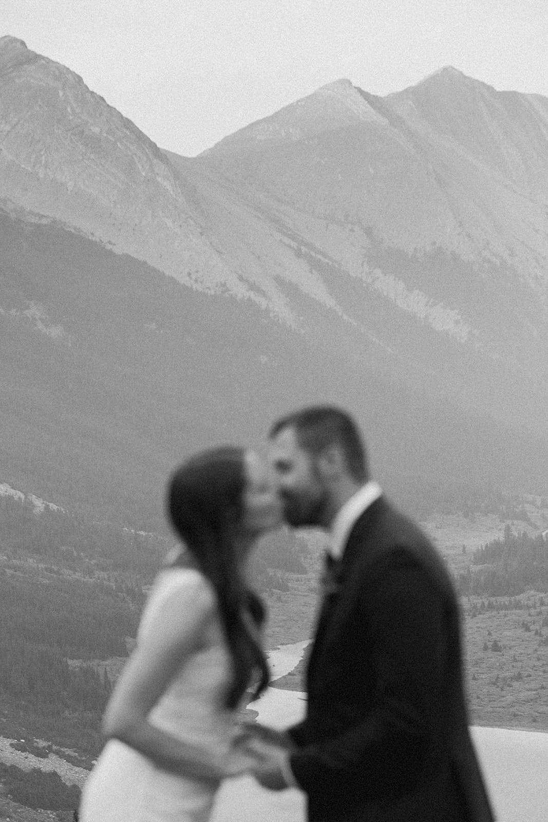 A Banff helicopter wedding couple kisses during their ceremony overlooking an alpine lake in Alberta.