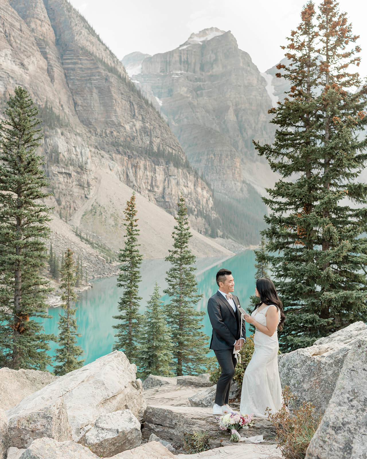 A Banff elopement couple in formal wedding attire smiles at one another during their vow ceremony. 