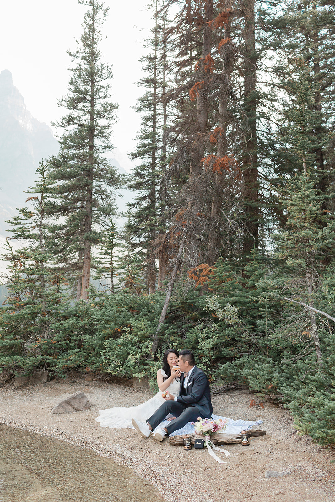 A bride feeds her groom a donut during their elopement picnic in Banff National Park. 