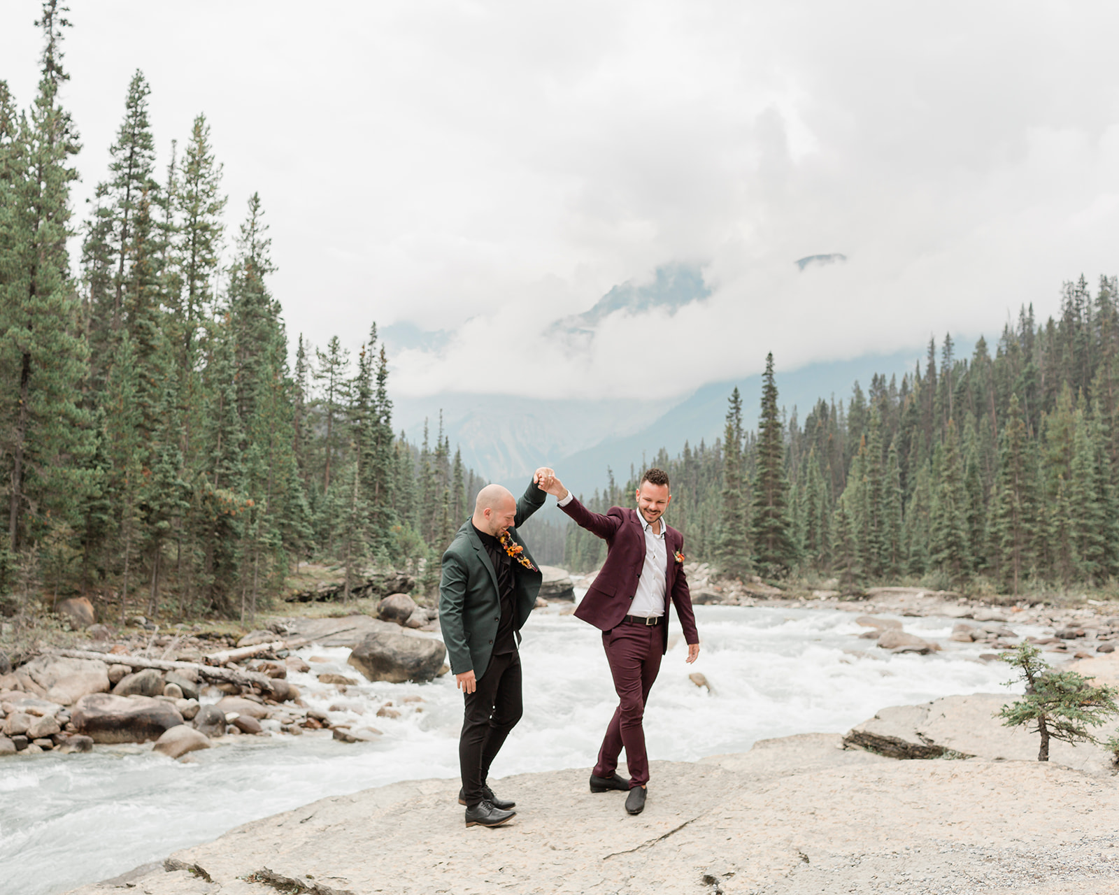 A Mistaya Canyon elopement couple holds hands while dancing. 