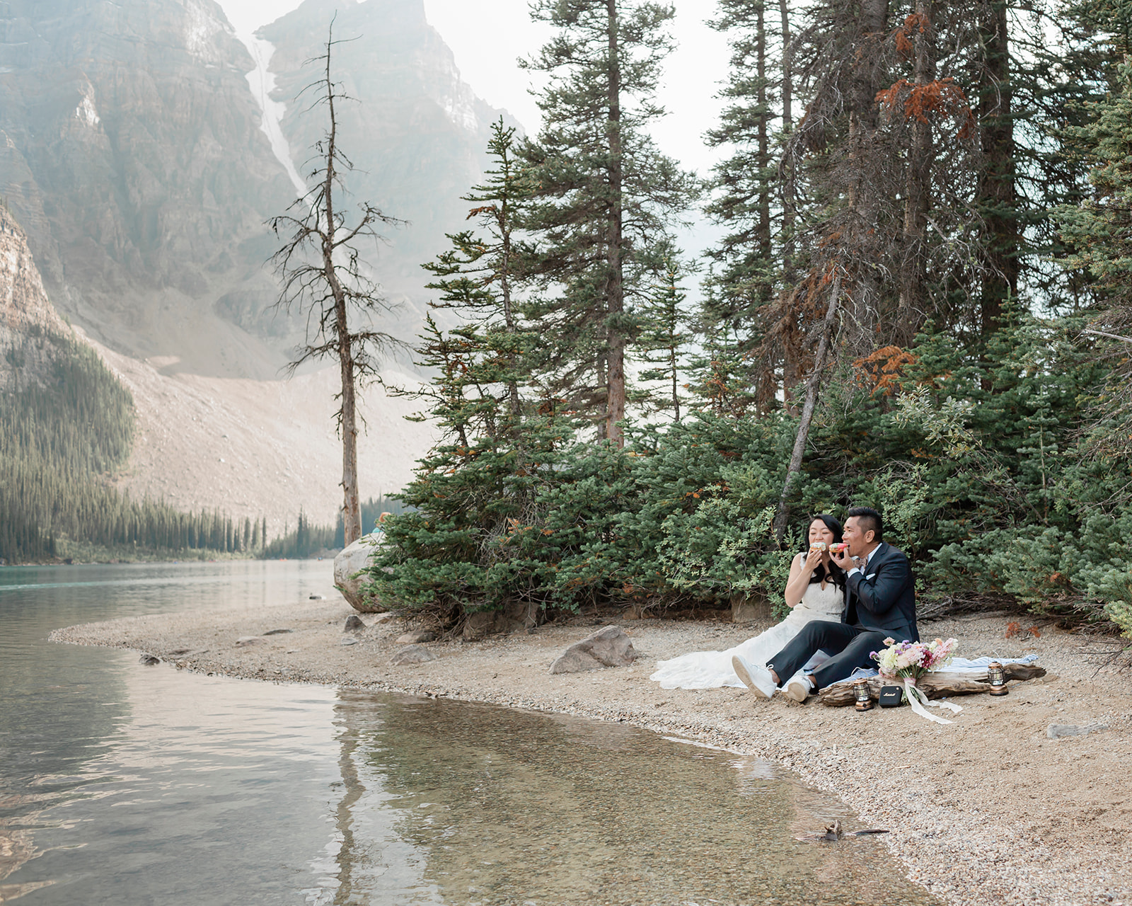 A bride and groom enjoy donuts during their elopement picnic in Banff National Park. 