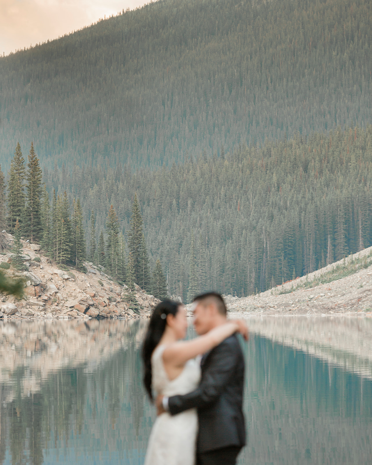 A bride and groom embrace during their Banff elopement near an alpine lake. 