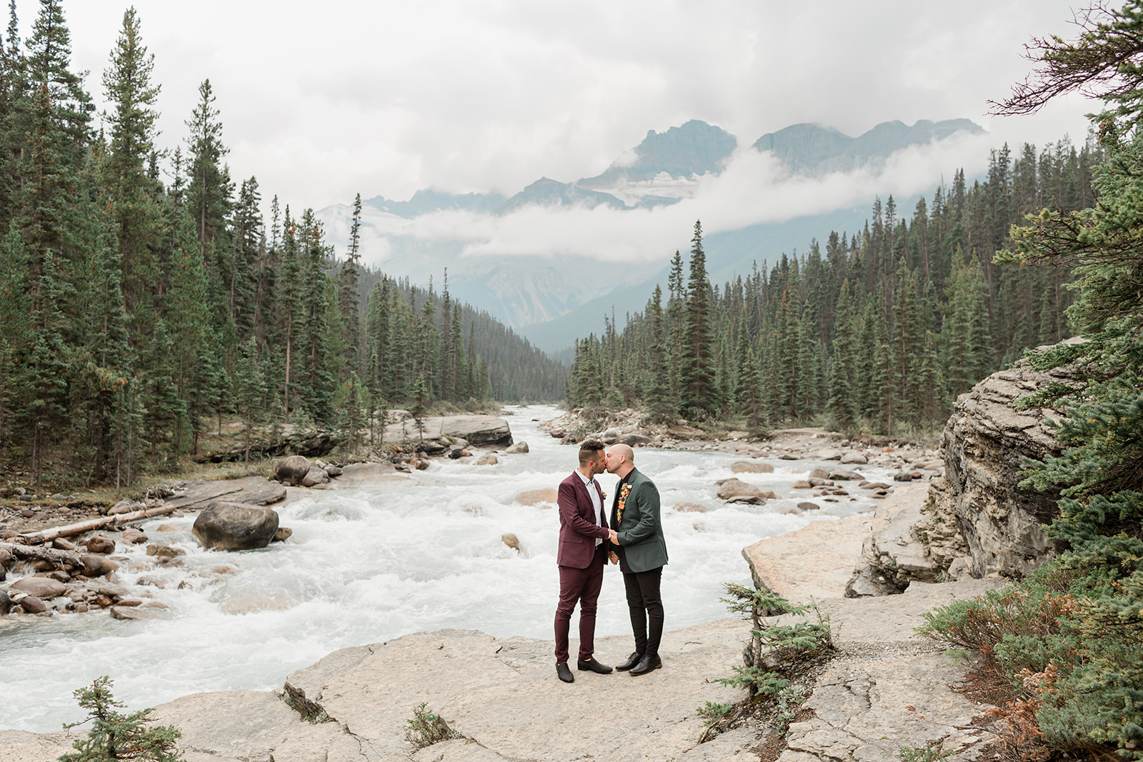 Grooms share a kiss near Mistaya Canyon during their Banff elopement.