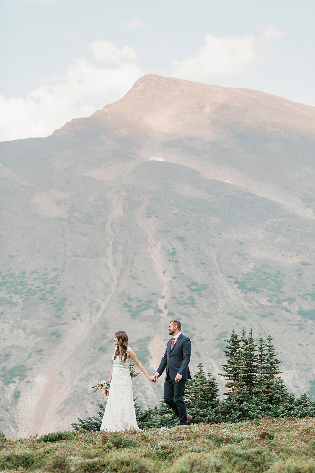 A couple holds hands while walking through Banff during their national park elopement in Alberta.