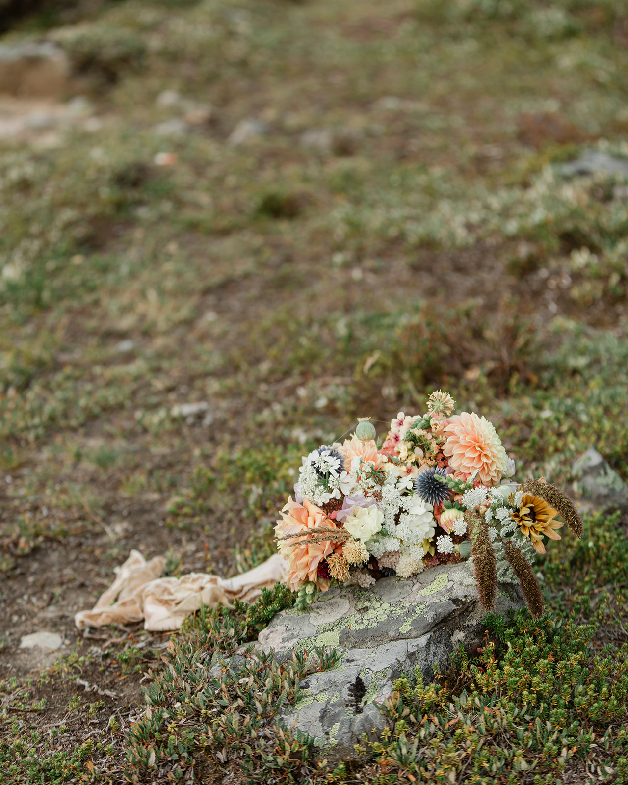 A bright bridal bouquet lying on a rock formation. 