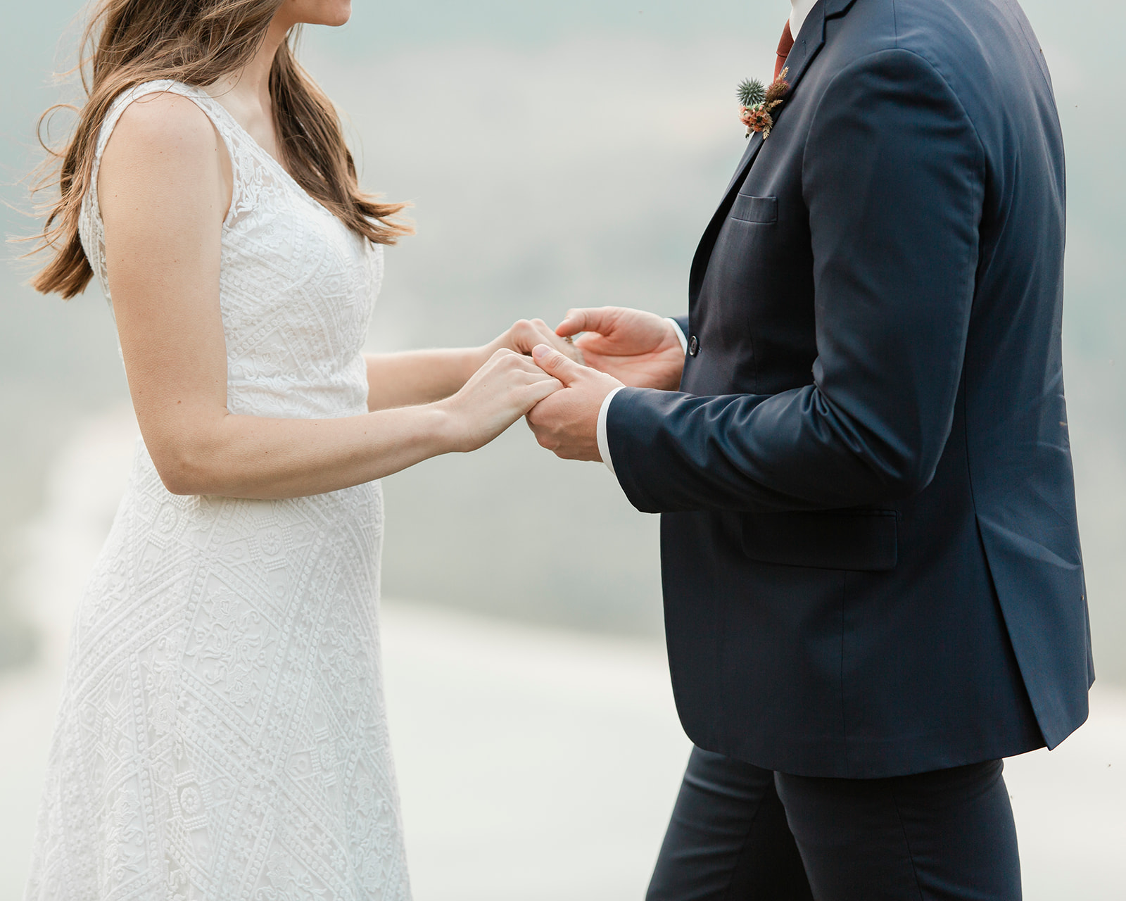 A couple dressed in formal elopement attire holds hands during their Alberta wedding. 