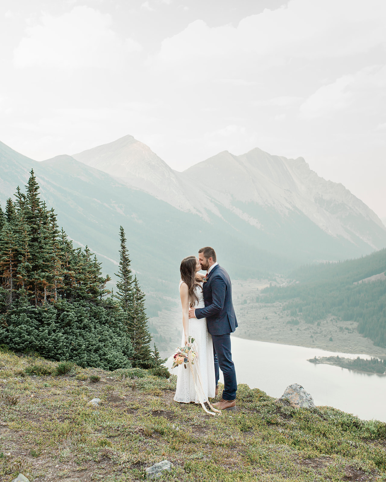 A newlywed couple kisses in Banff National Park during their sustainable wedding in Alberta. 