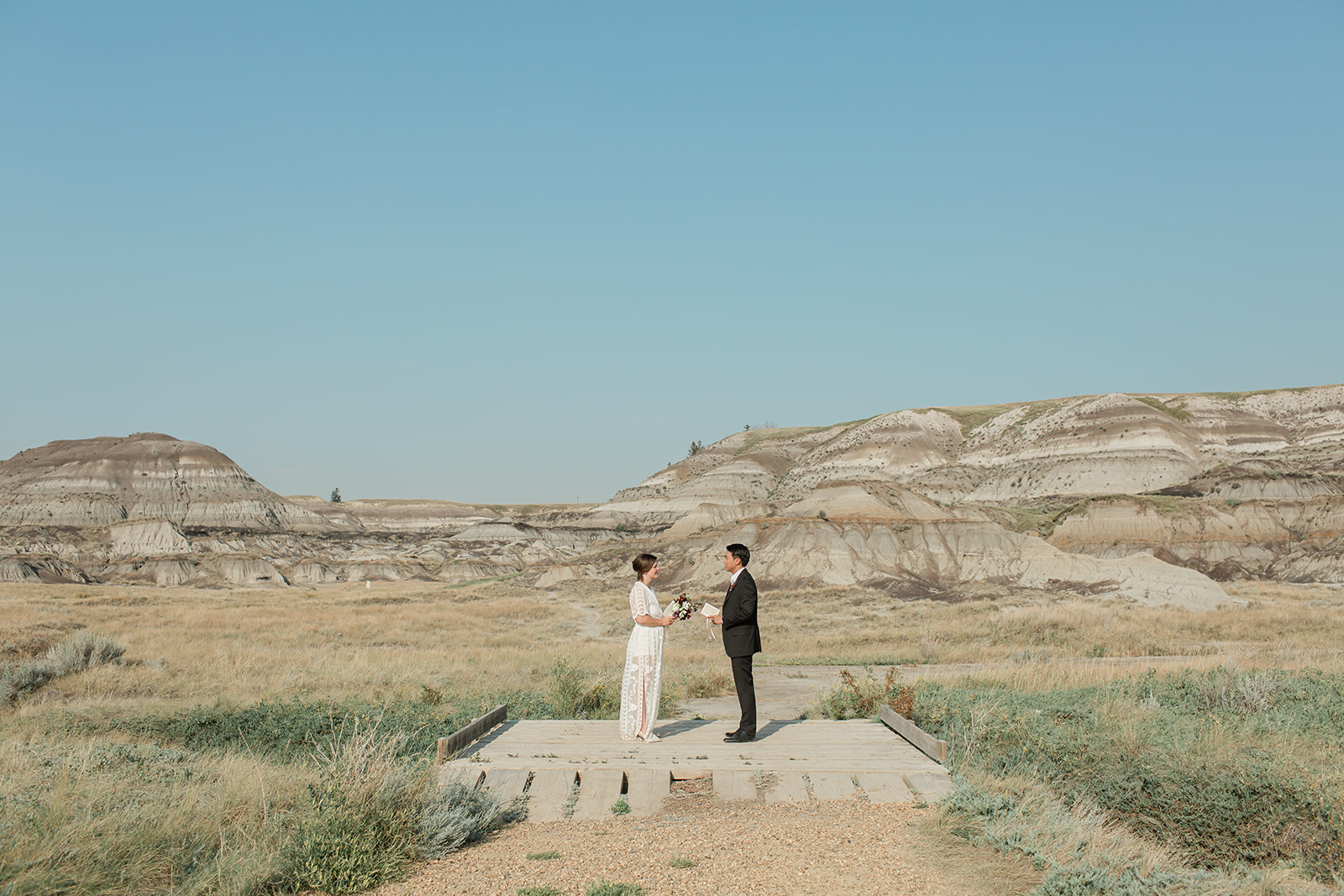 An elopement couple dressed in cultural wedding attire recites their vows on a bridge in Horsethief Canyon in Alberta, Canada.