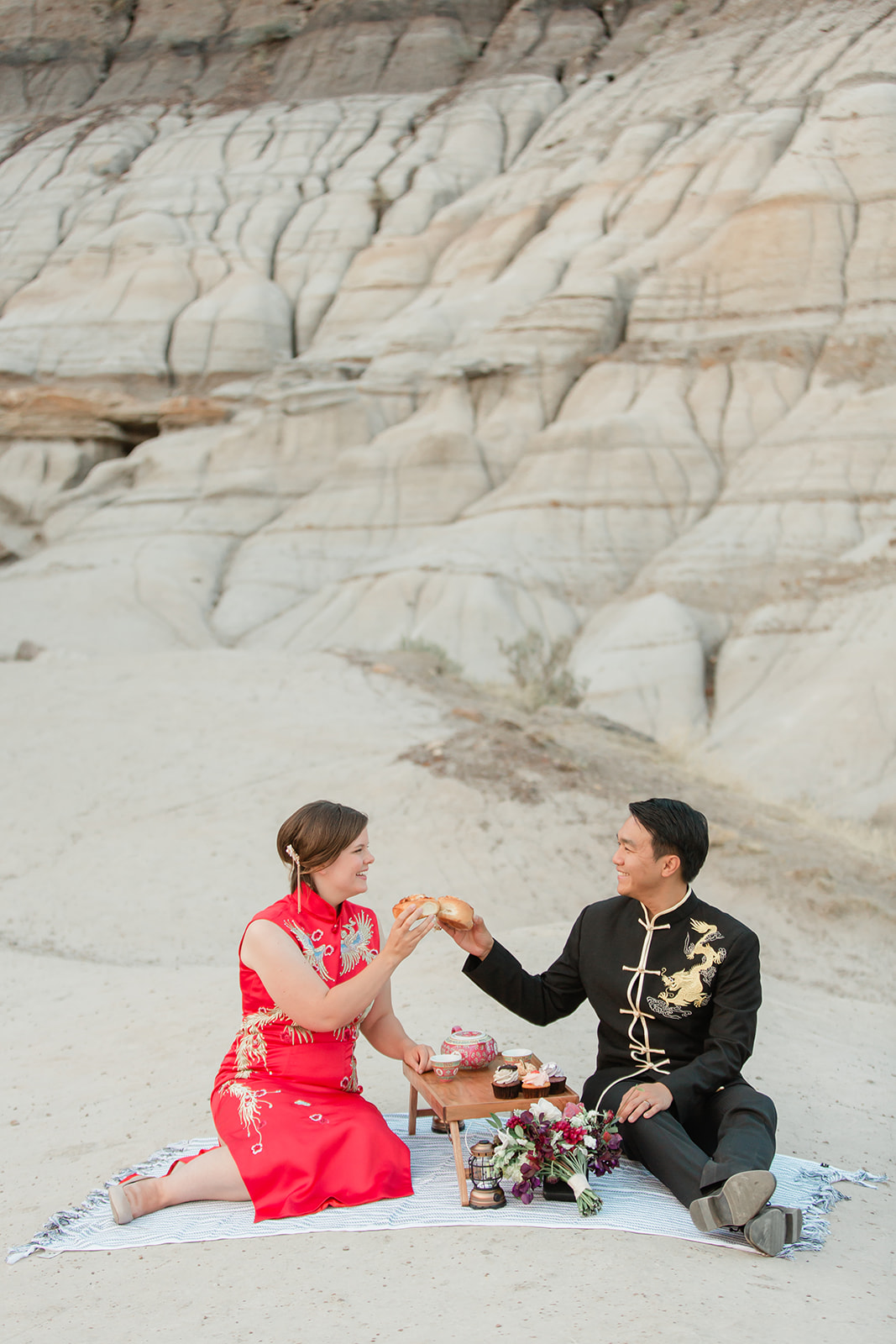 An elopement couple dressed in cultural wedding attire enjoys a picnic in Horsethief Canyon in Alberta, Canada.