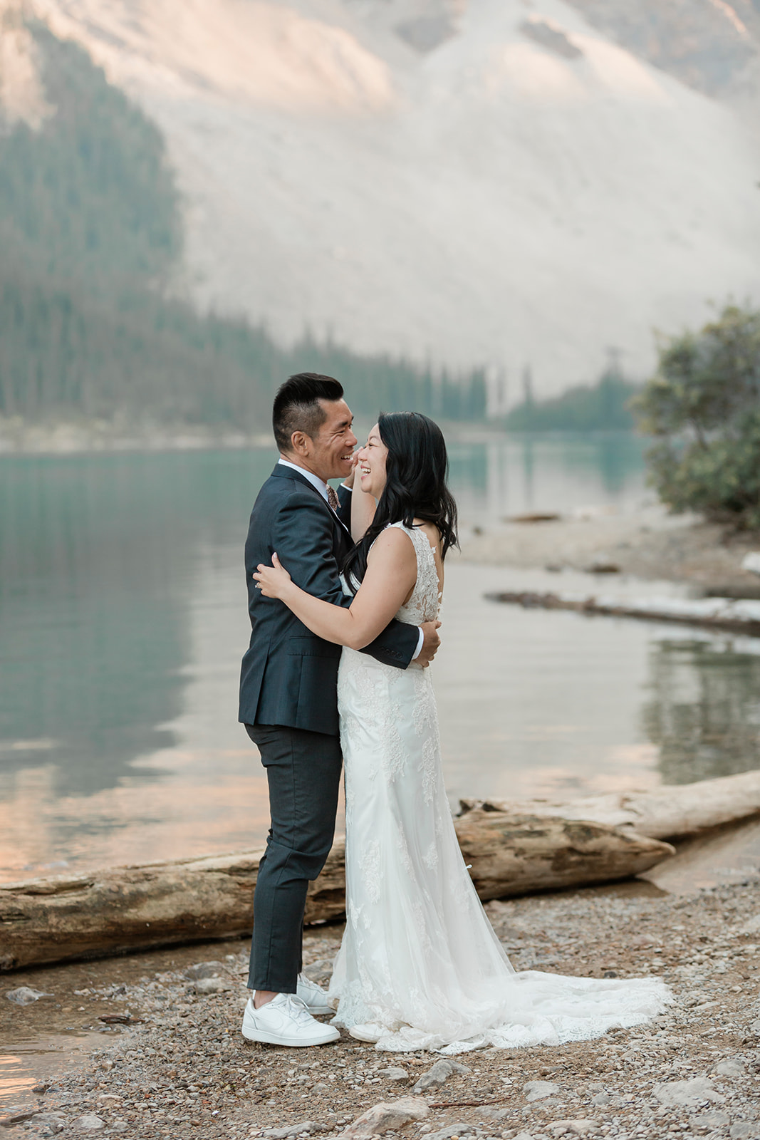 A groom wearing a suit dances with his bride near Moraine Lake in Banff National Park.