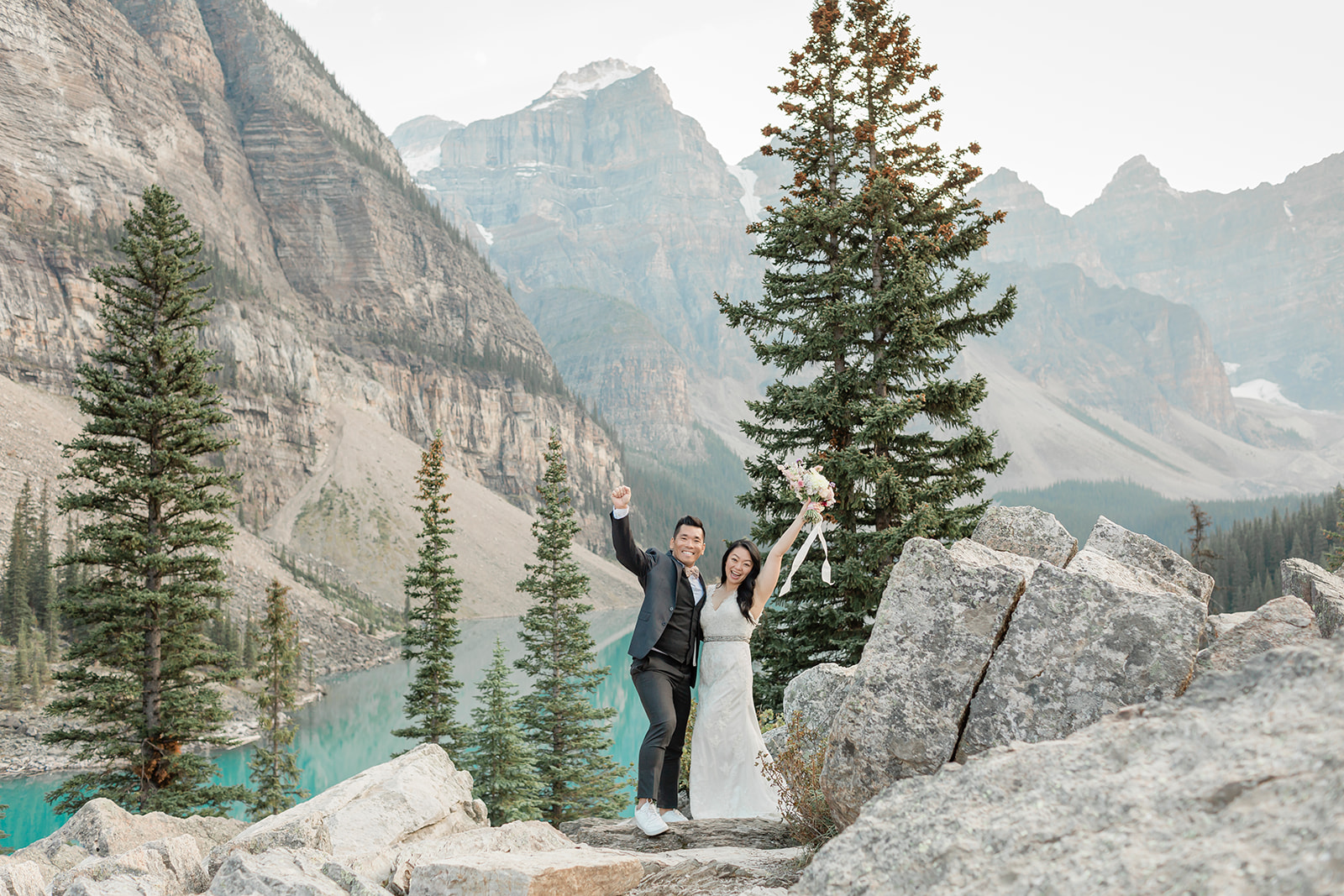 A couple dressed in formal wedding attire celebrates their elopement in Banff National Park at Moraine Lake.