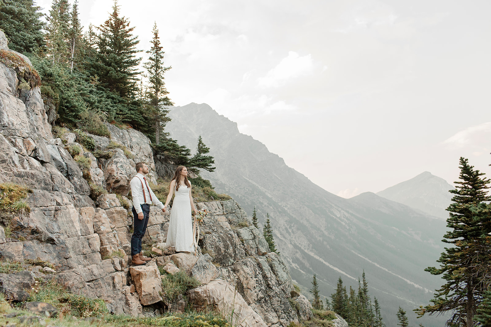 An adventure elopement couple stands on a cliff's edge in Banff National Park.