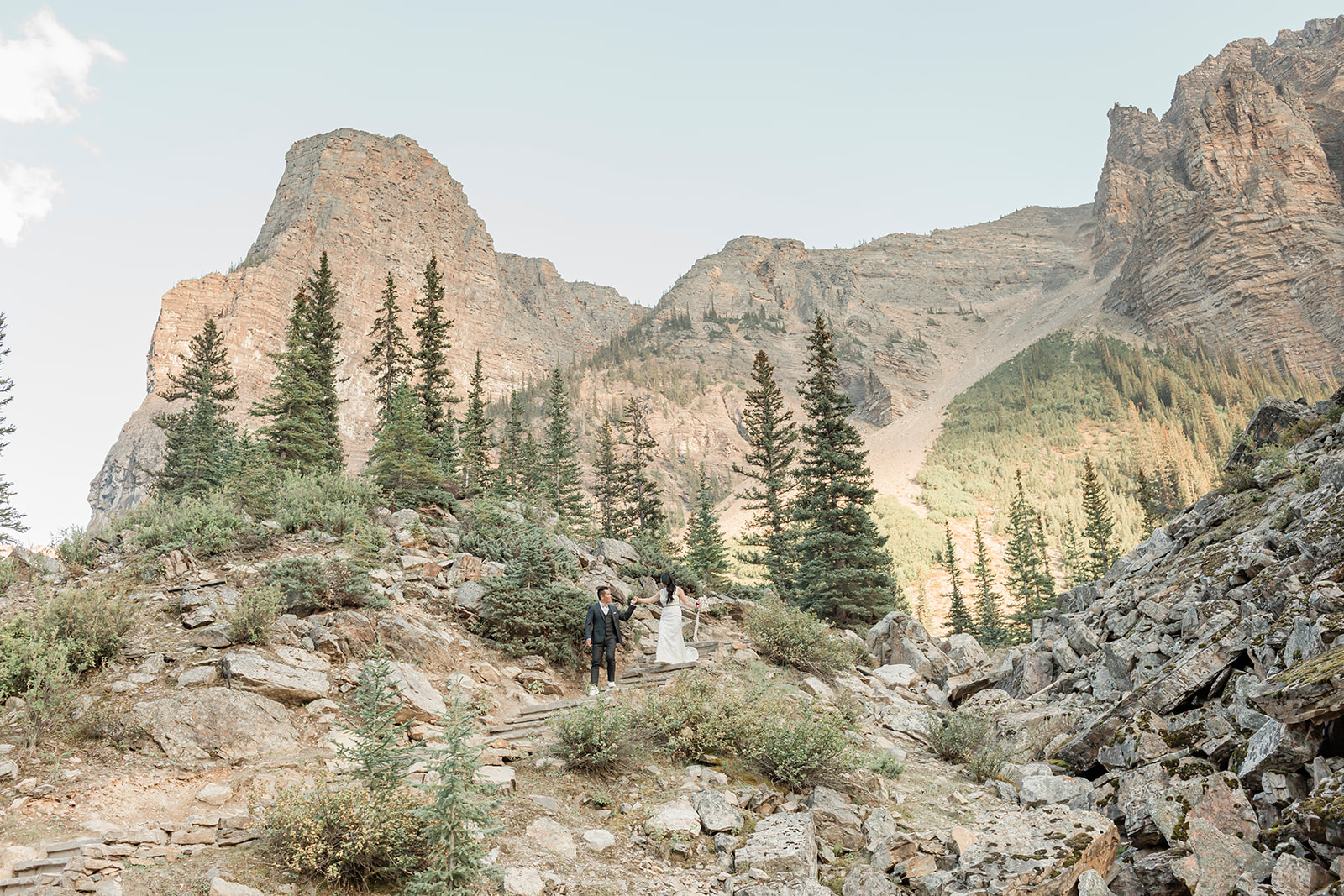 A hiking elopement couple holds hands while walking down stairs in Banff National Park. 