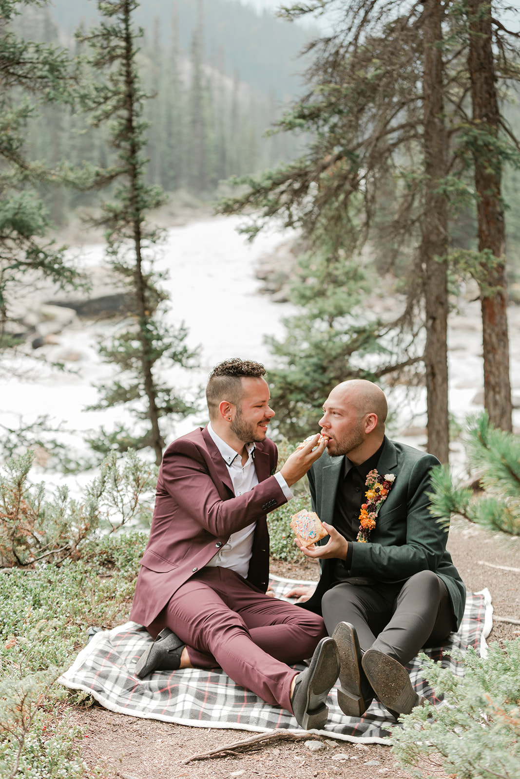 An Alberta elopement couple shares pastries during a picnic at Mistaya Canyon. 