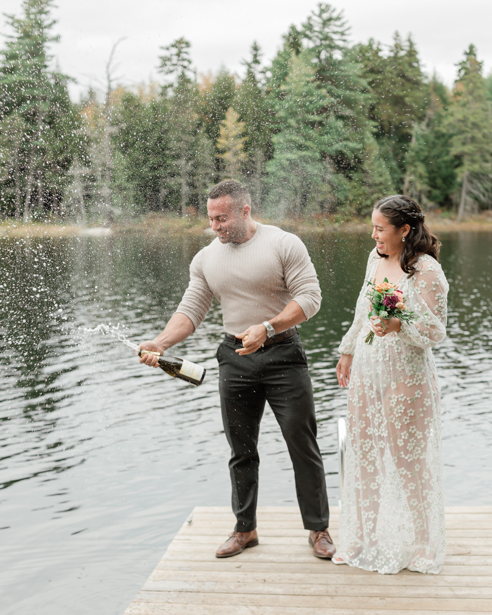 A couple that just got married in Haliburton Forest and are celebrating with a champagne pop