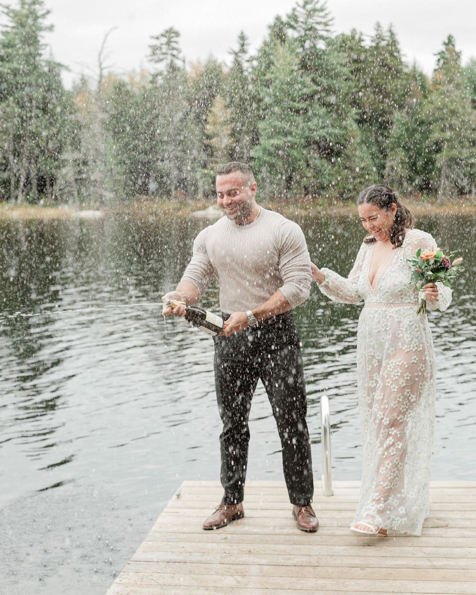 A couple that just got married in Haliburton Forest and are celebrating with a champagne pop