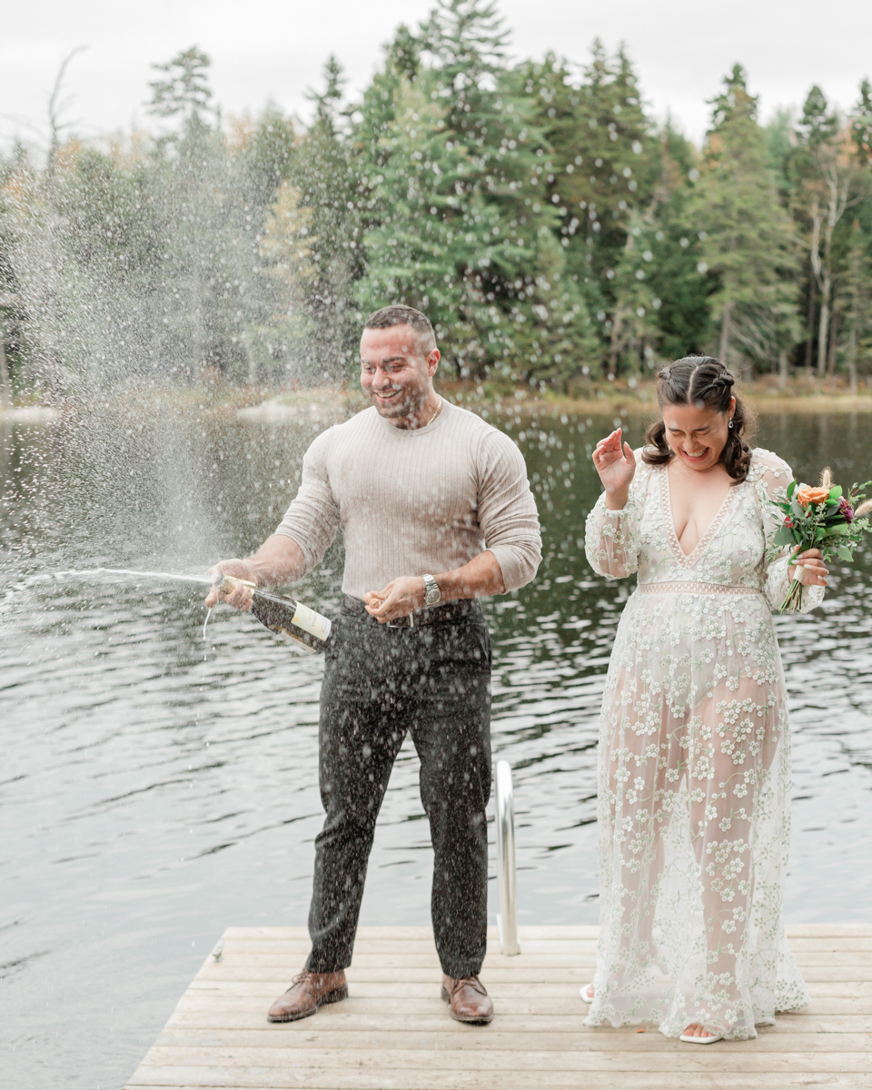 A couple that just got married in Haliburton Forest and are celebrating with a champagne pop