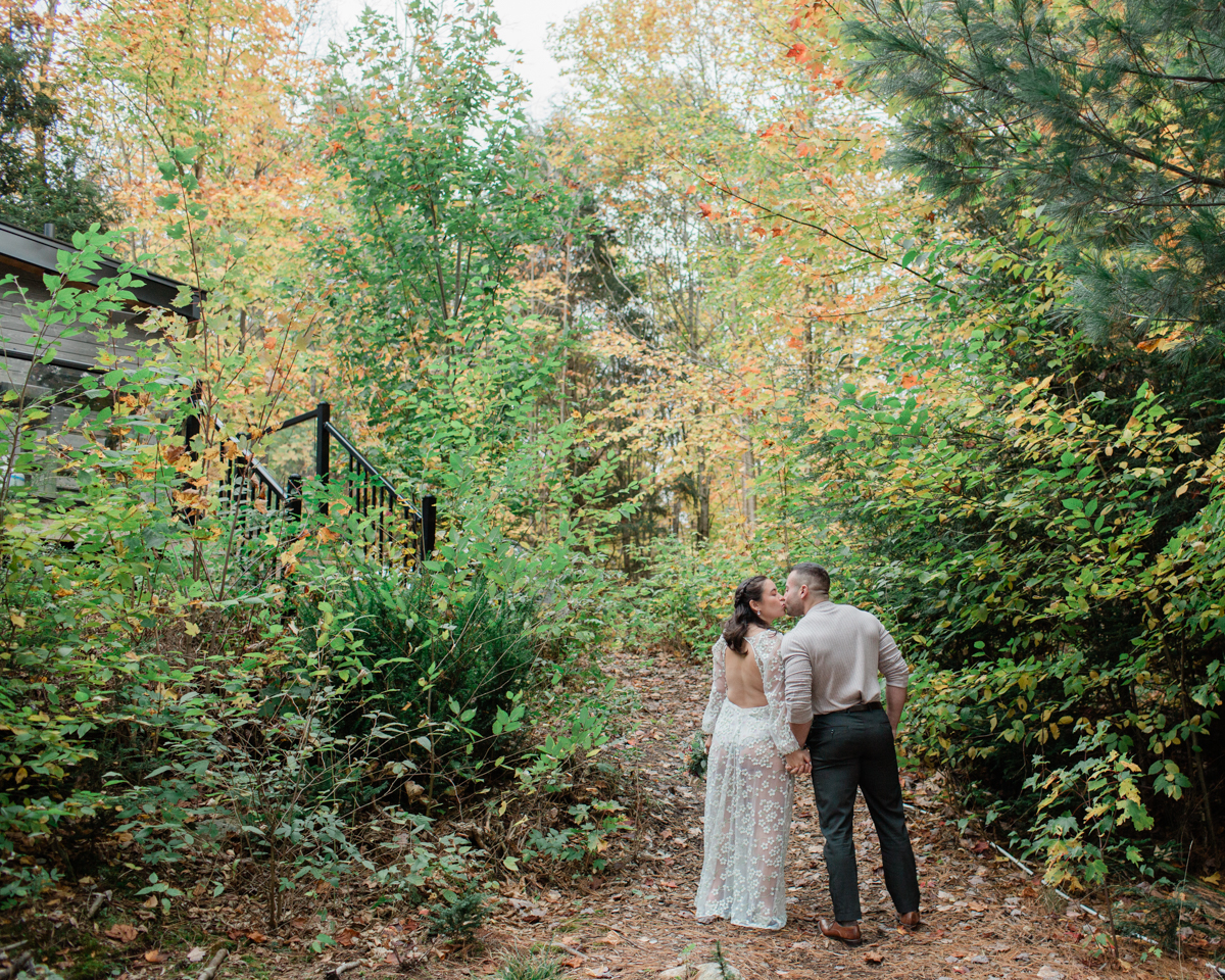 A couple kissing in front of their Muskoka off grid cabin after their wedding 