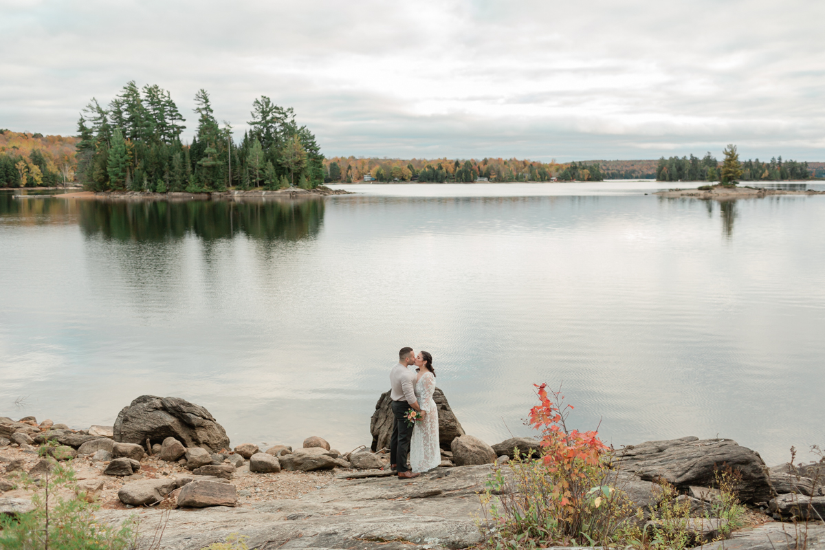 A couple kissing on a Muskoka lakefront after their wedding 