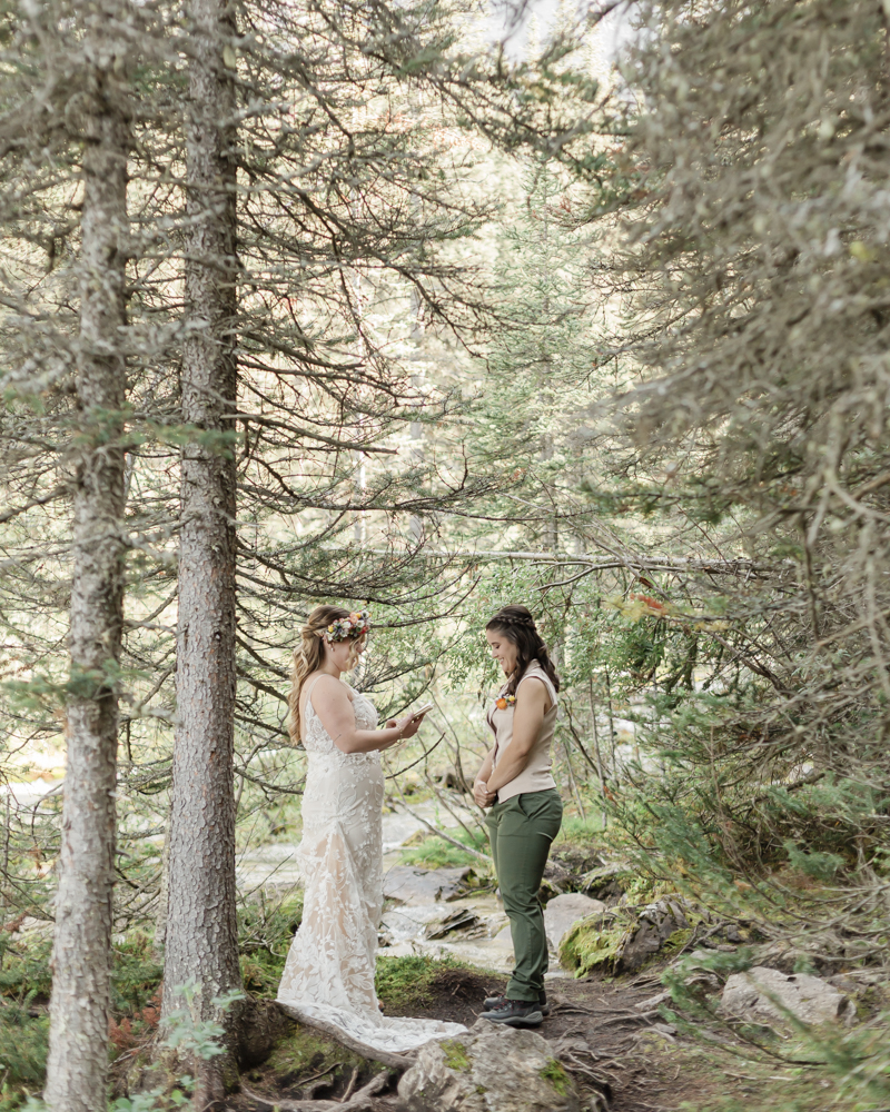 A couple exchanging vows and rings for their LGBTQ+ waterfall Banff elopement