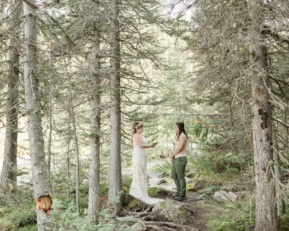 A couple exchanging vows and rings for their LGBTQ+ waterfall Banff elopement