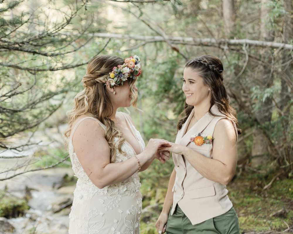 A couple exchanging vows and rings for their LGBTQ+ waterfall Banff elopement