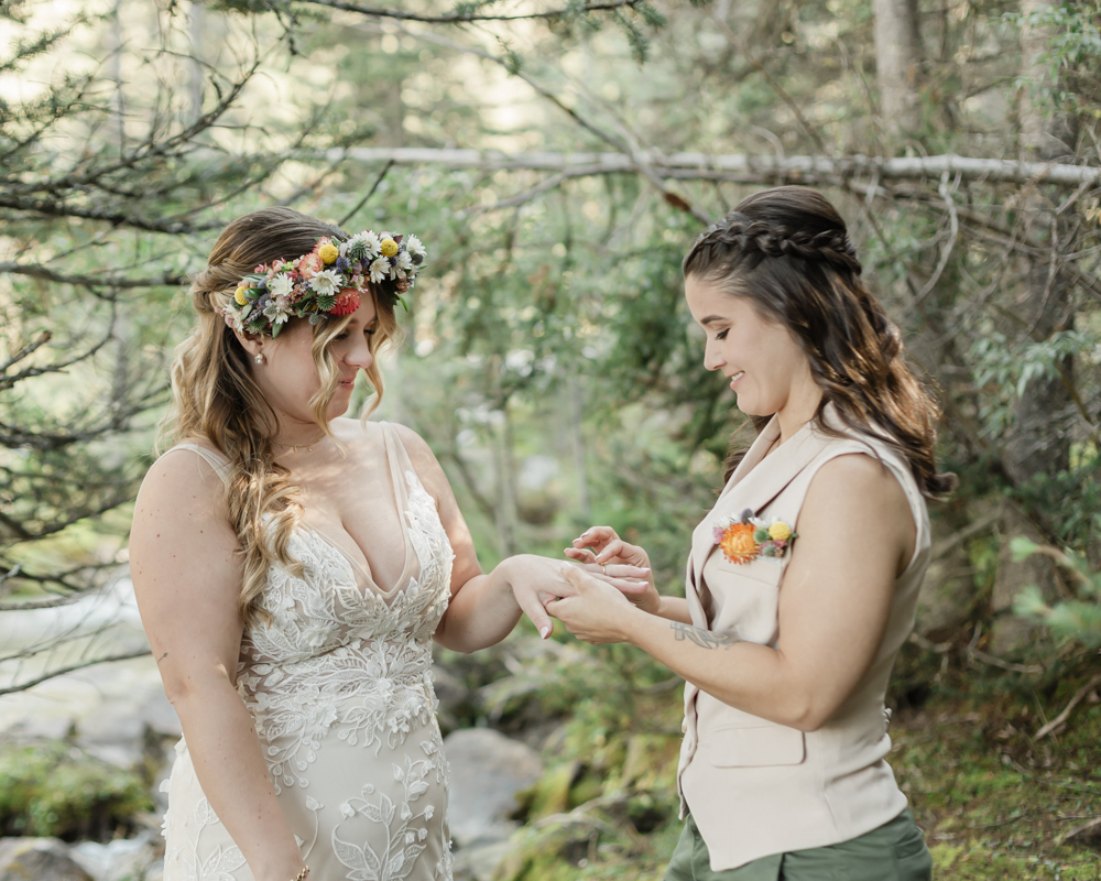 A couple exchanging vows and rings for their LGBTQ+ waterfall Banff elopement