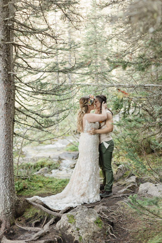 A couple exchanging vows and rings for their LGBTQ+ waterfall Banff elopement