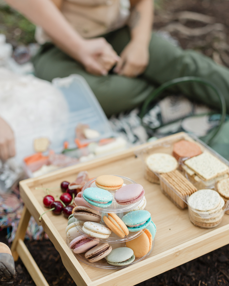 A couple enjoying a macaron and charcuterie picnic at Moraine Lake for their LGBTQ+ Banff elopement