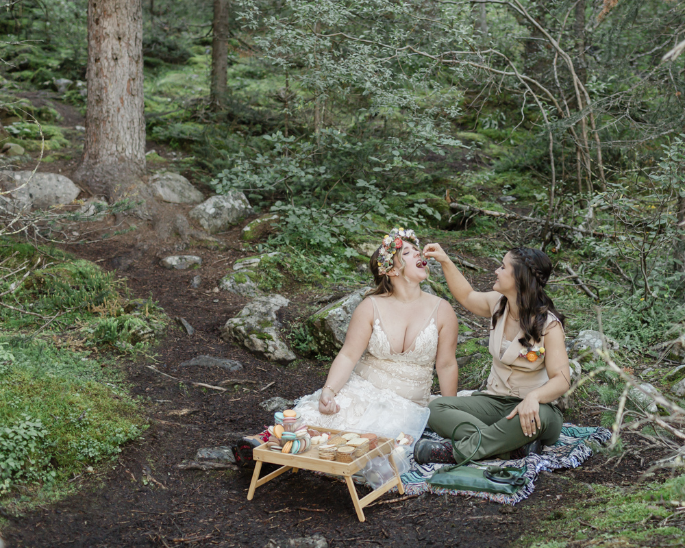 A couple enjoying a macaron and charcuterie picnic at Moraine Lake for their LGBTQ+ Banff elopement