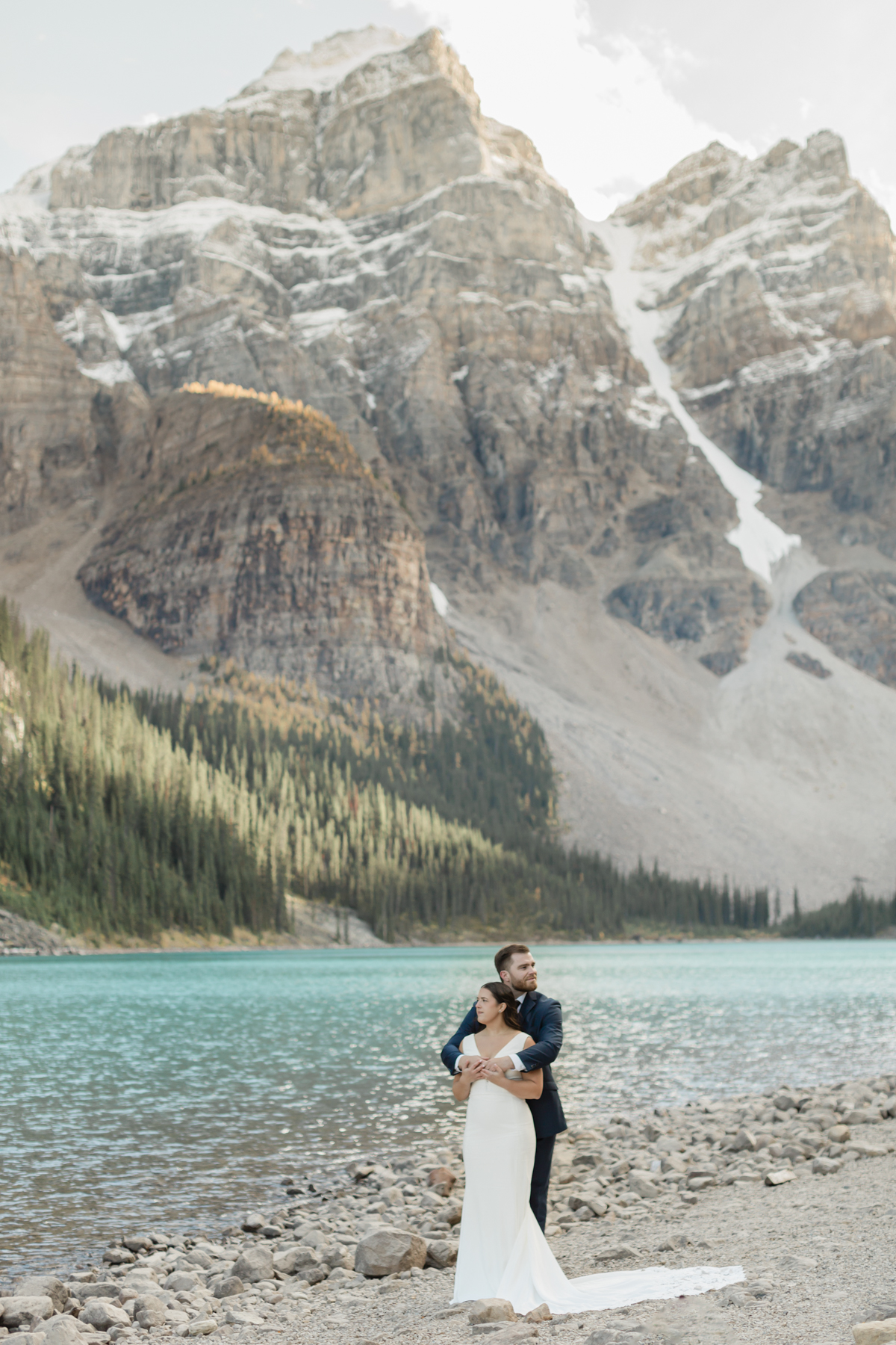 A couple posing looking at the mountains at Moraine Lake during their elopement 