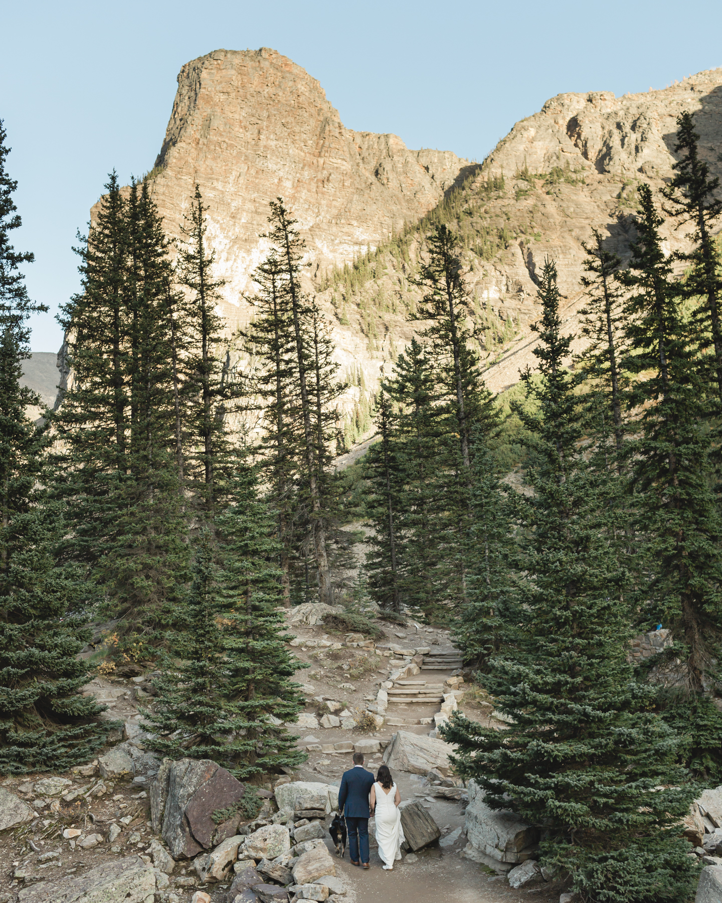 A walking up the rockpile trail at Moraine Lake during their elopement 