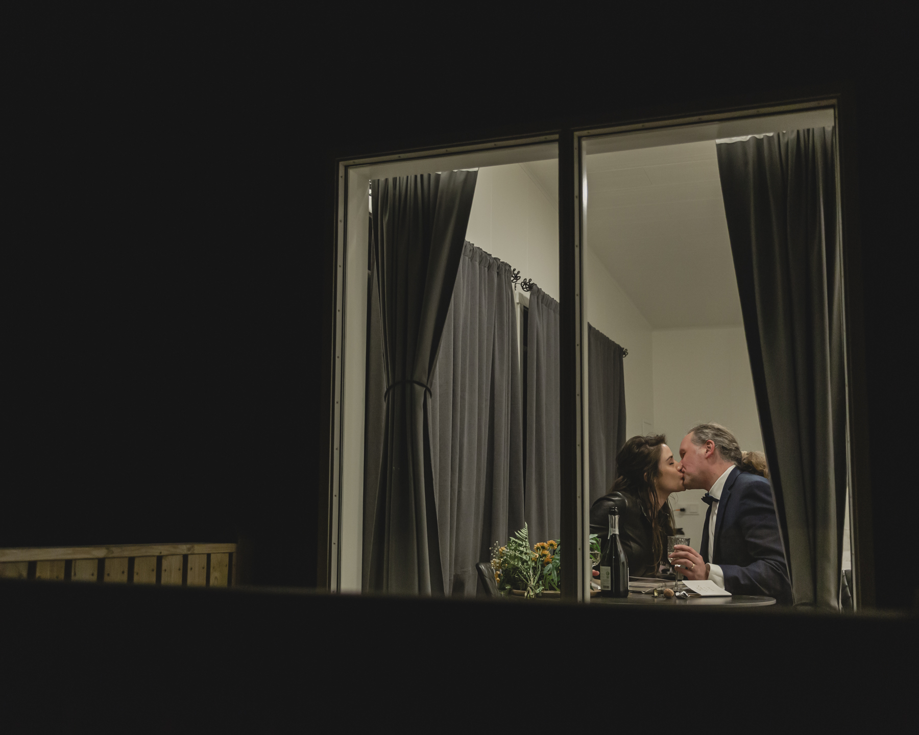 A couple exchanging gifts and celebrating with champagne at their airbnb after their Iceland wedding near Kirkjufell