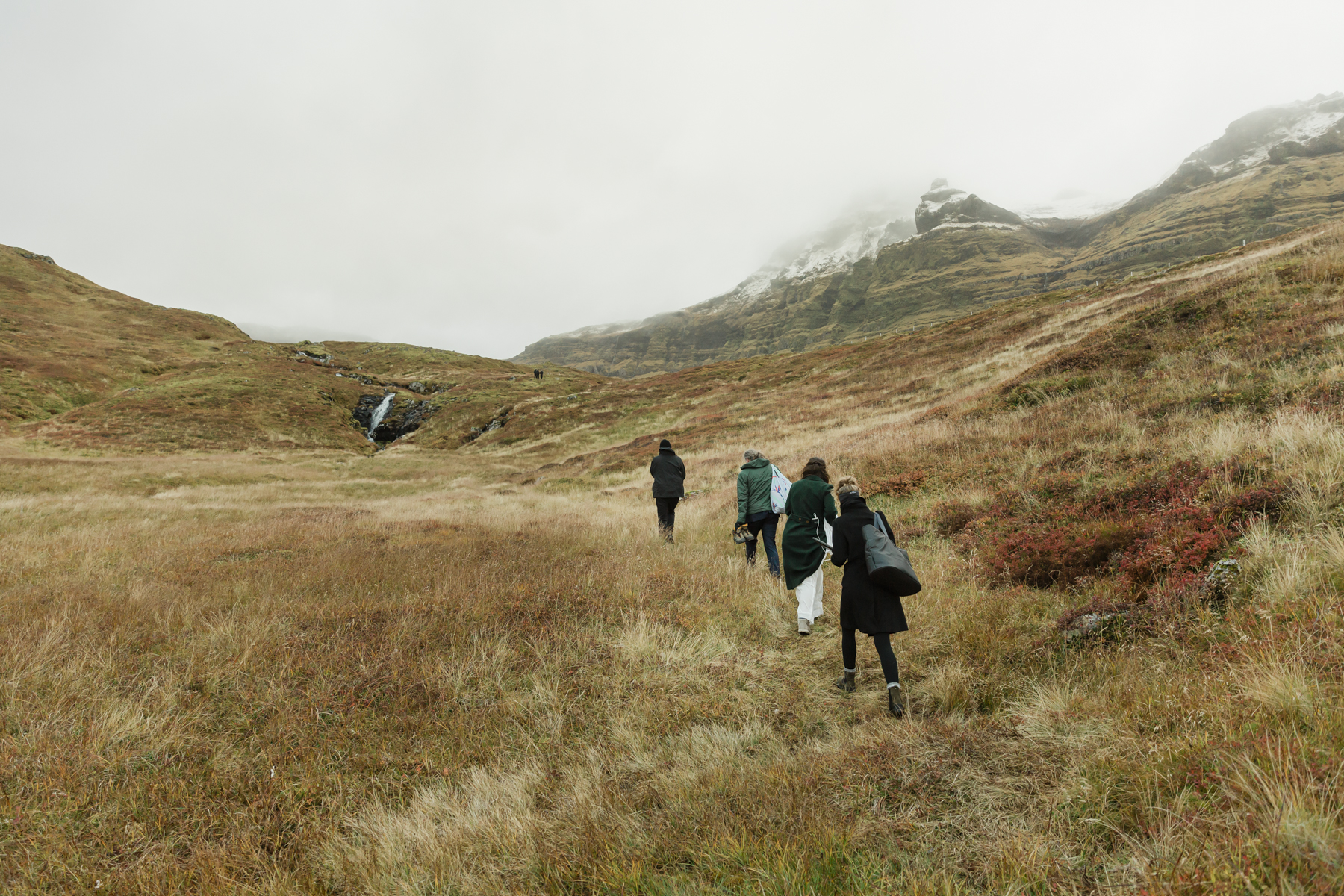 A group walking towards a private waterfall near Kirkjufell mountain for a couples elopement