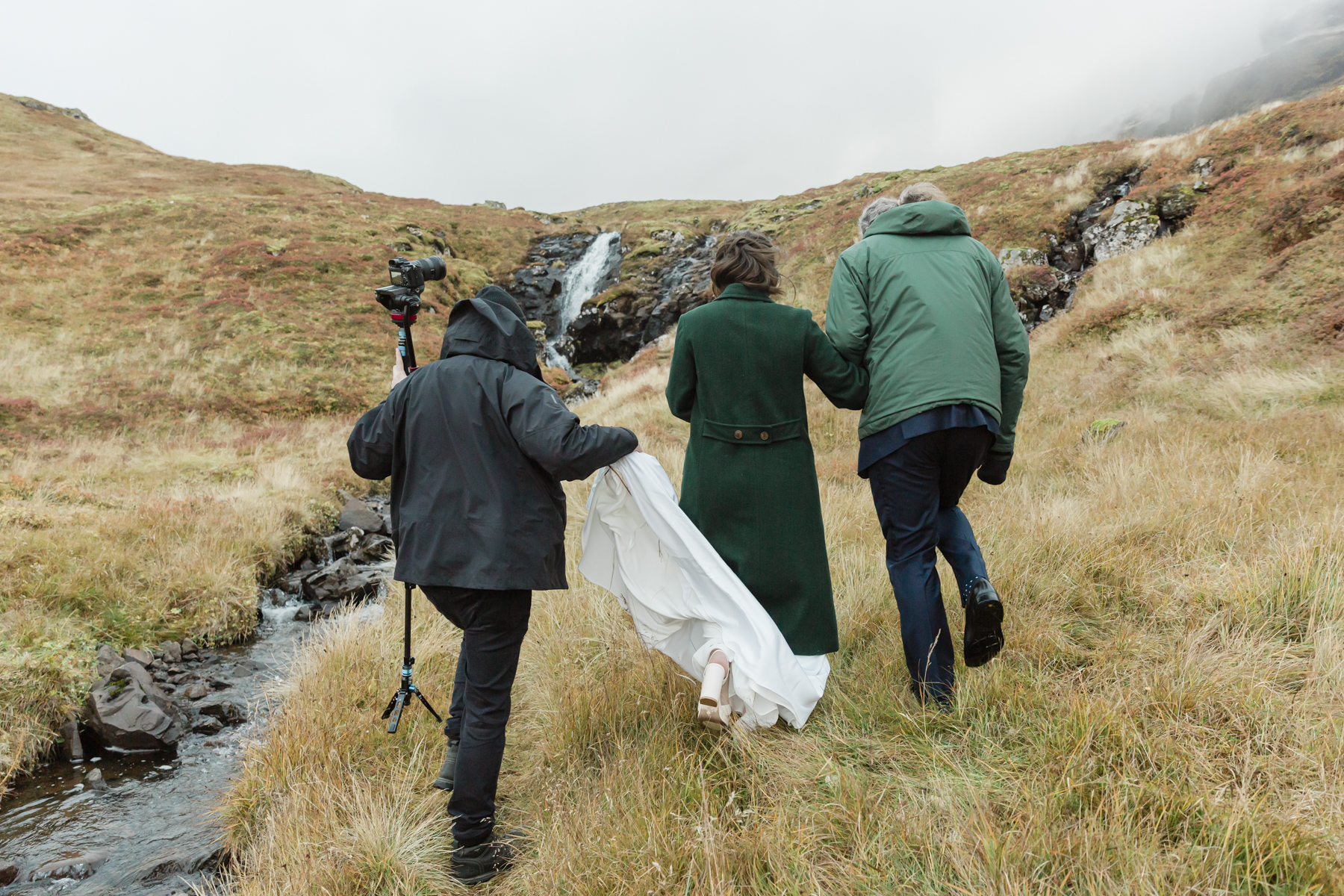 A group walking towards a private waterfall near Kirkjufell mountain for a couples elopement