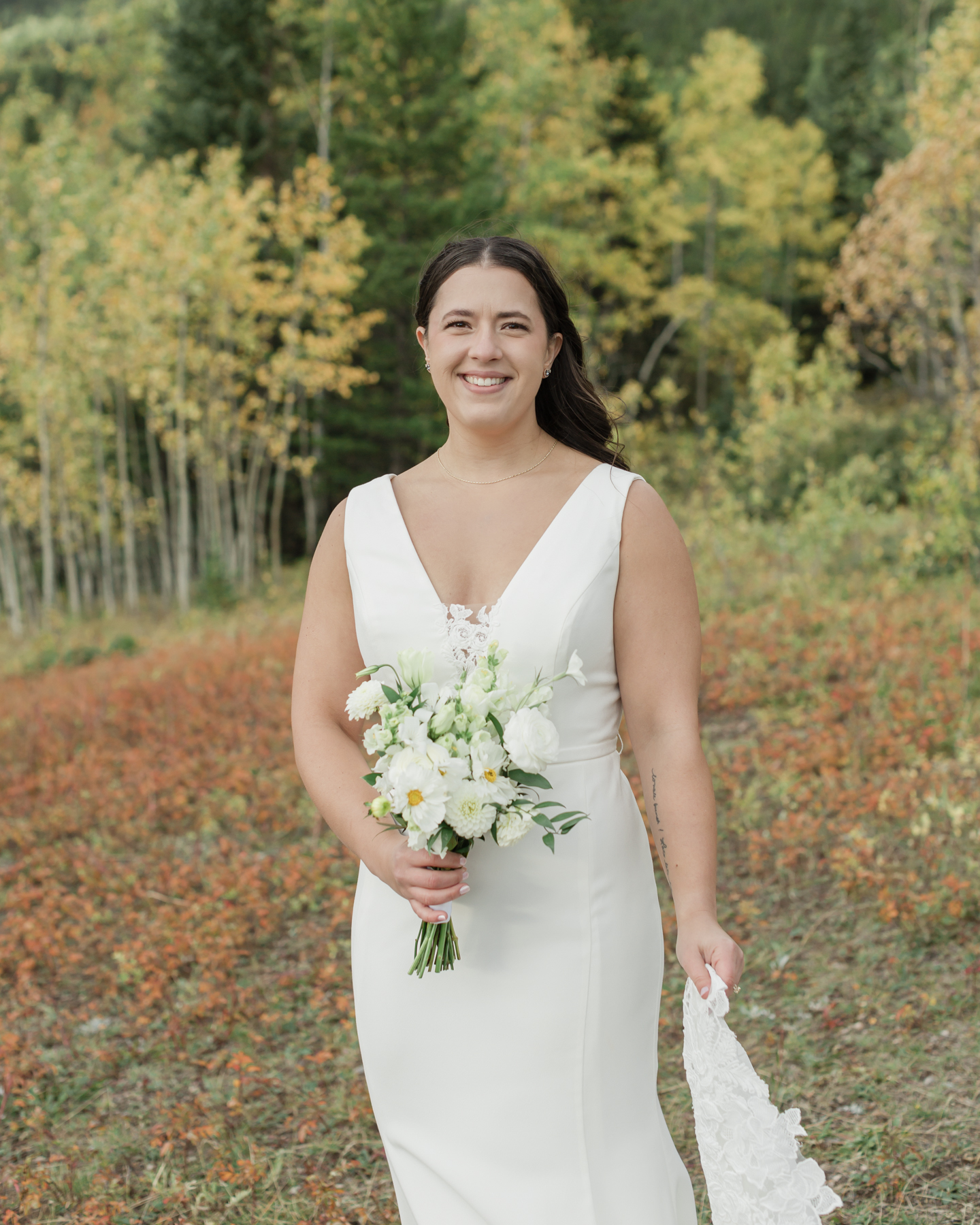 A couple looking at the camera and smiling during their Kananaskis Country ceremony