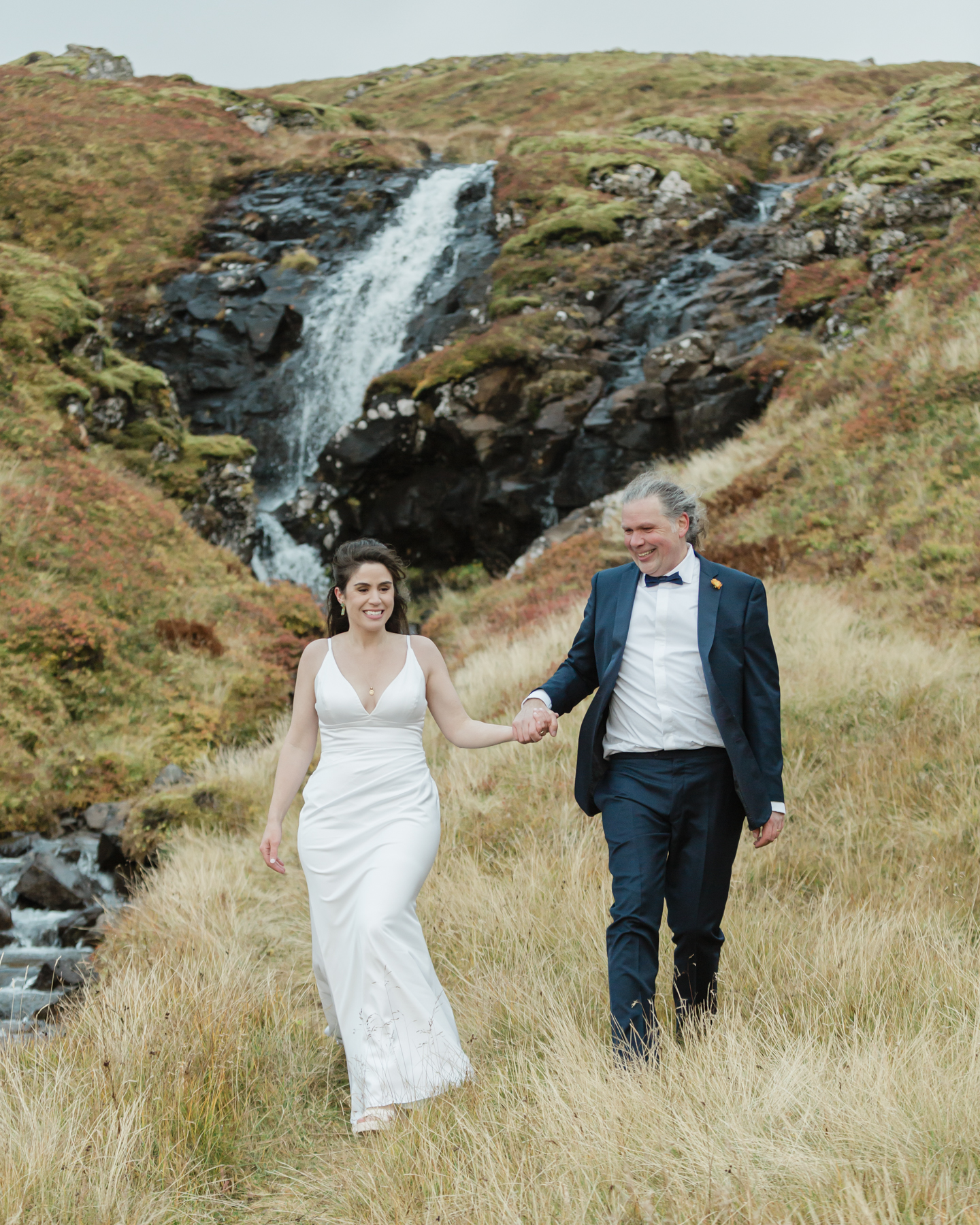 A couple walking away from a secluded waterfall in Iceland