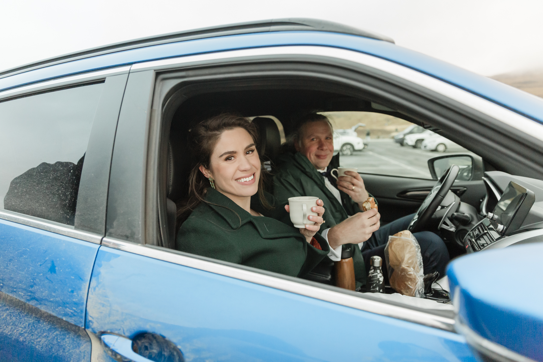 A couple warming up in the car with hot coffee and snacks during their Iceland wedding on the Snæfellsnes Peninsula 