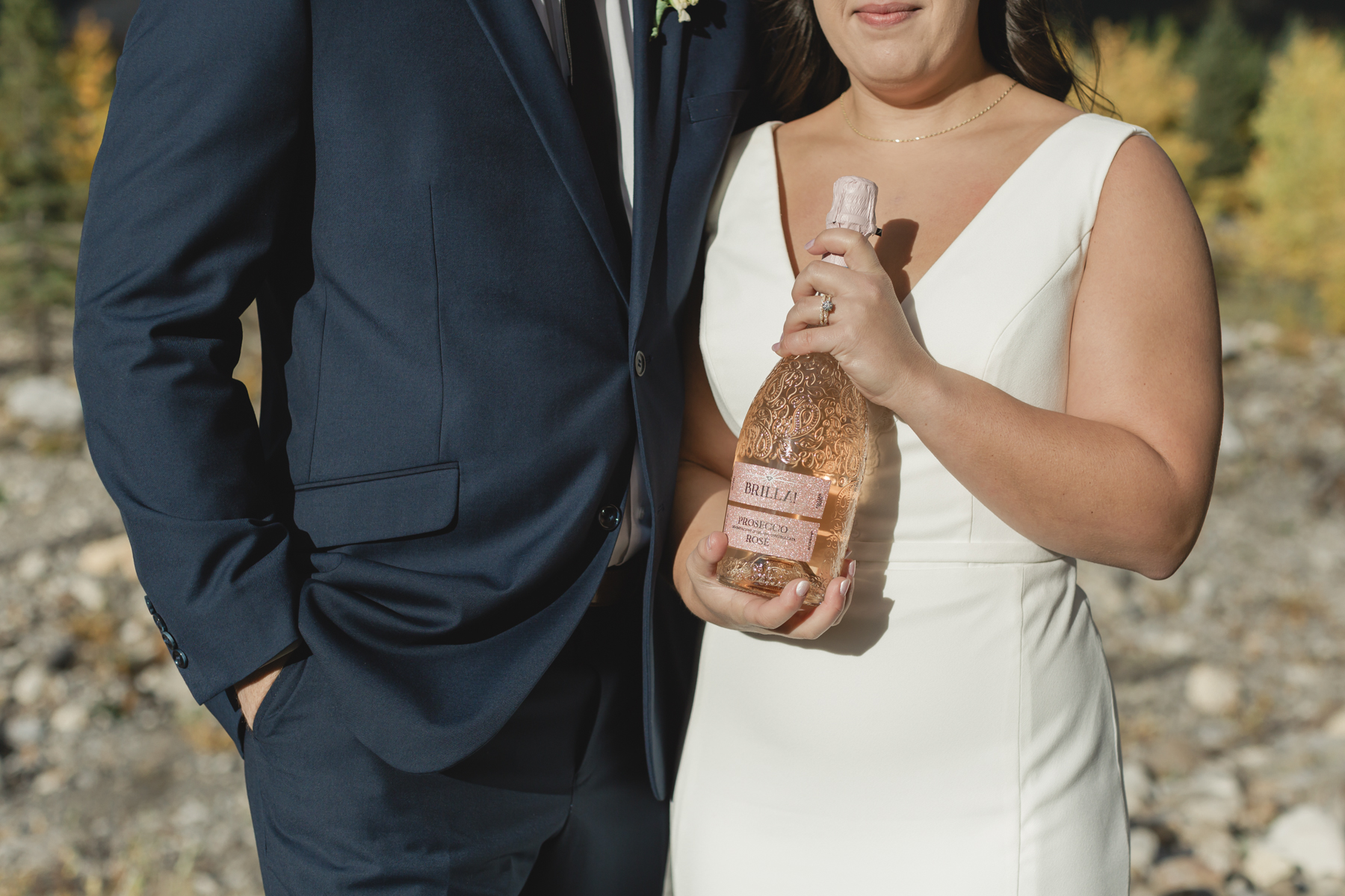 A couple celebrating with a champagne pop during their elopement near Mount Kidd