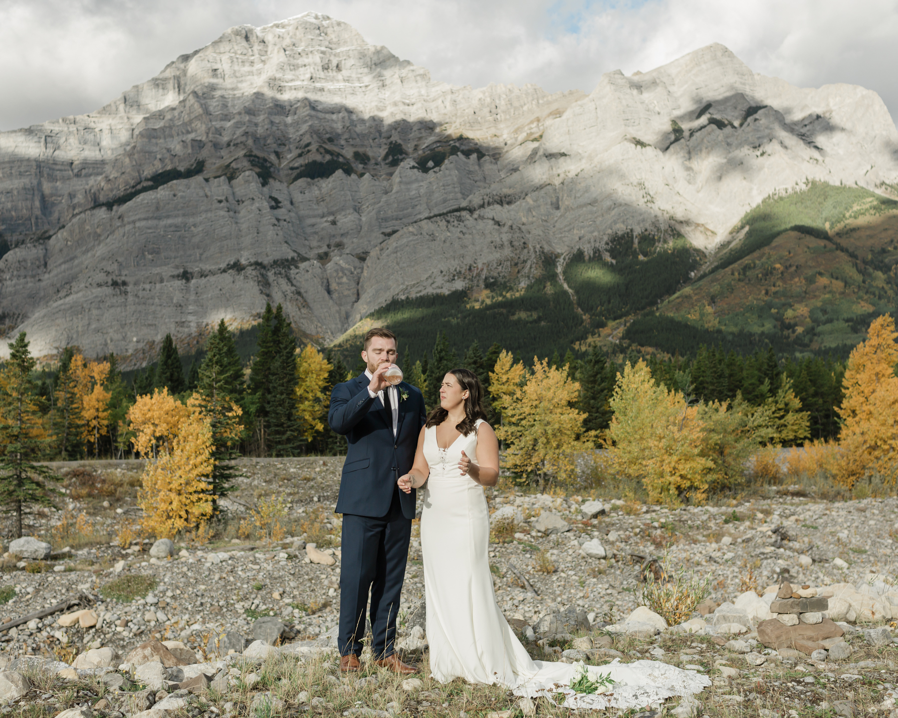 A couple celebrating with a champagne pop during their elopement near Mount Kidd