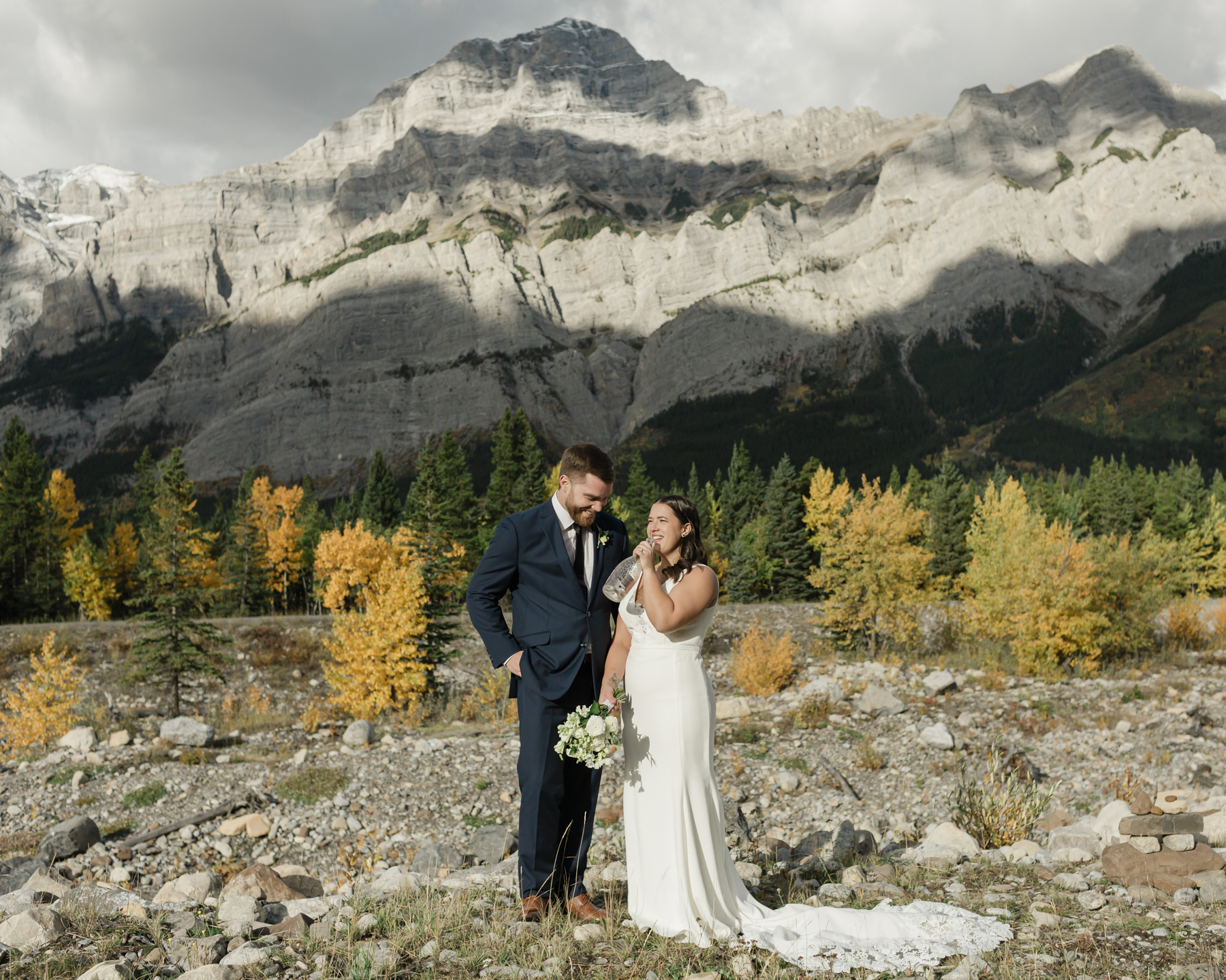 A couple celebrating with a champagne pop during their elopement near Mount Kidd