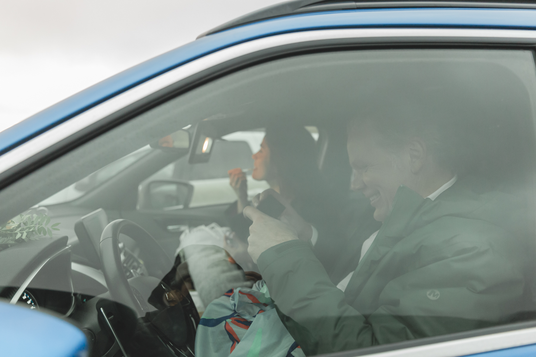 A couple warming up in the car with hot coffee and snacks during their Iceland wedding on the Snæfellsnes Peninsula 