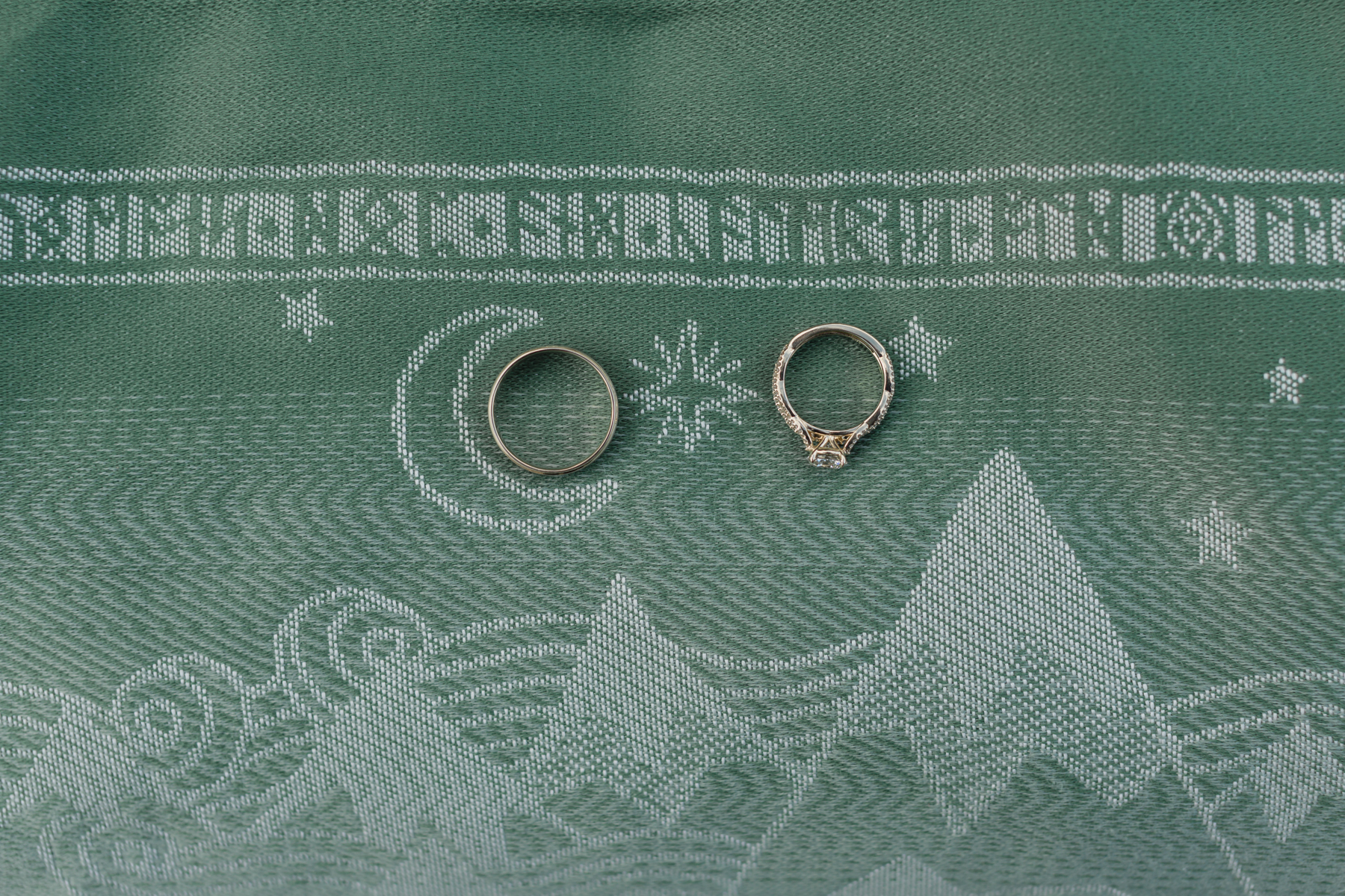 A couple's wedding rings on a mountain scape scarf with lord of the rings runes on it