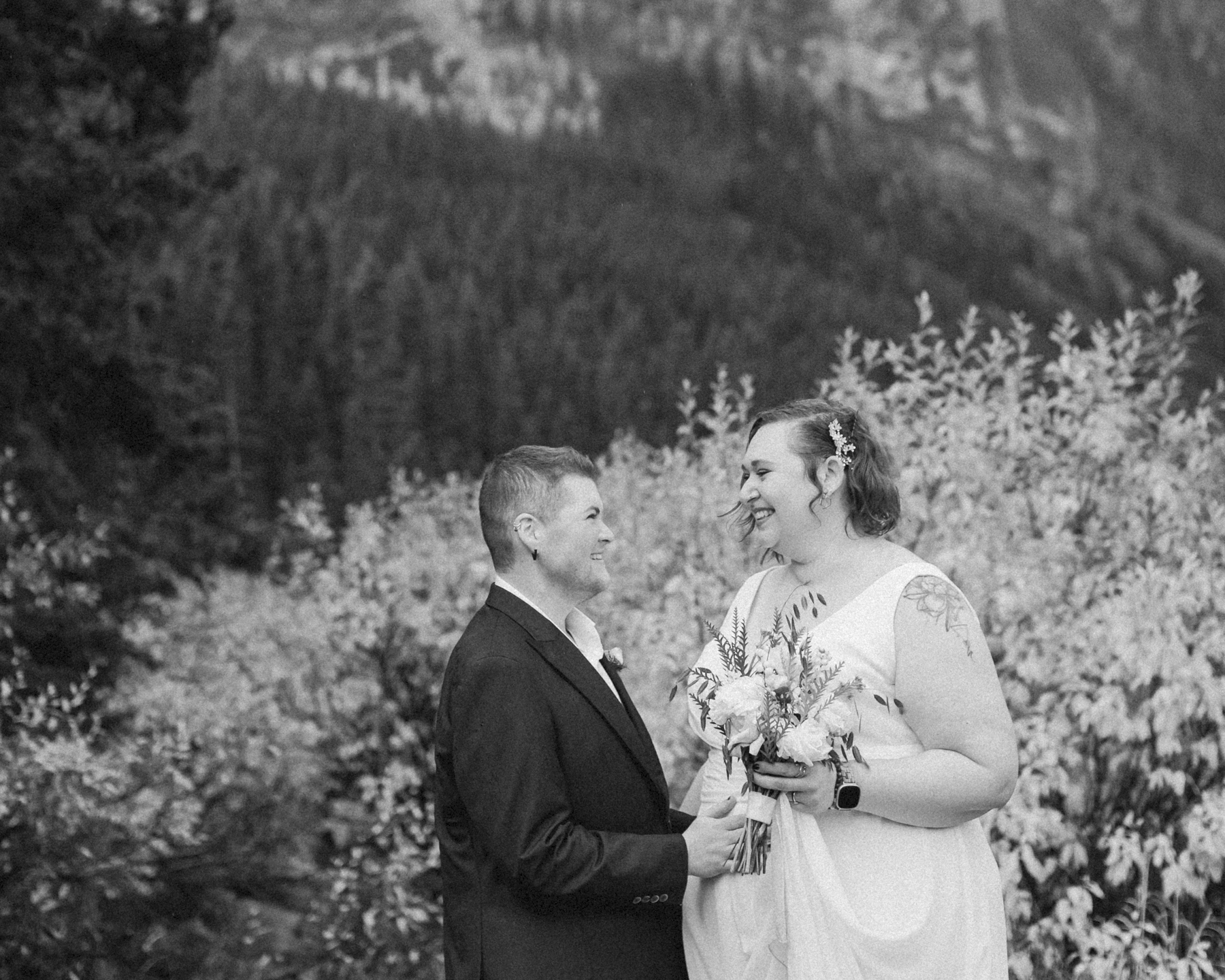 A LGBTQIA+ couple laughing together at Lake Louise in autumn