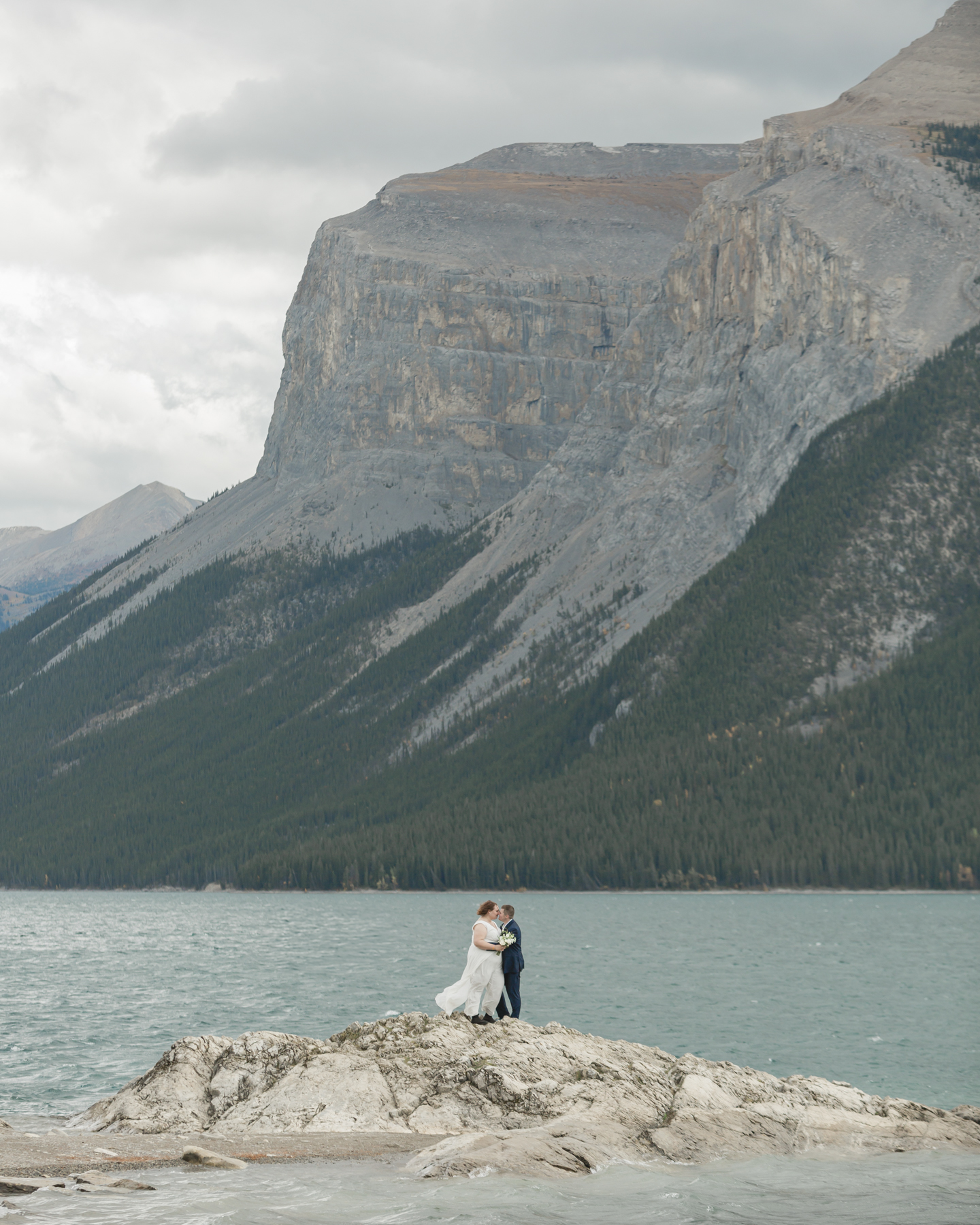 A LGBTQIA+ couple after their wedding exploring Lake Minnewanka 